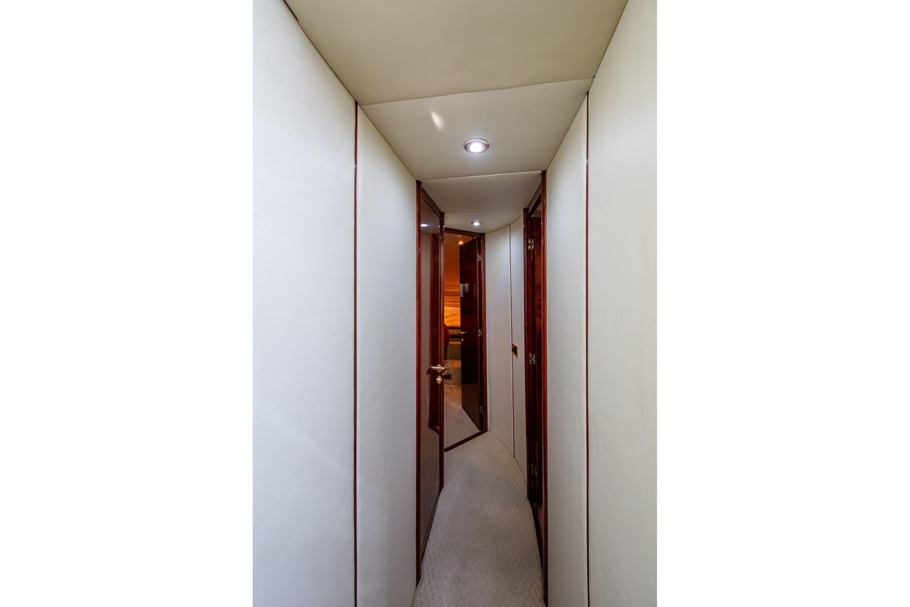 Narrow hallway inside 2000 Fairline Squadron 52 yacht, featuring sleek wooden doors and modern lighting.