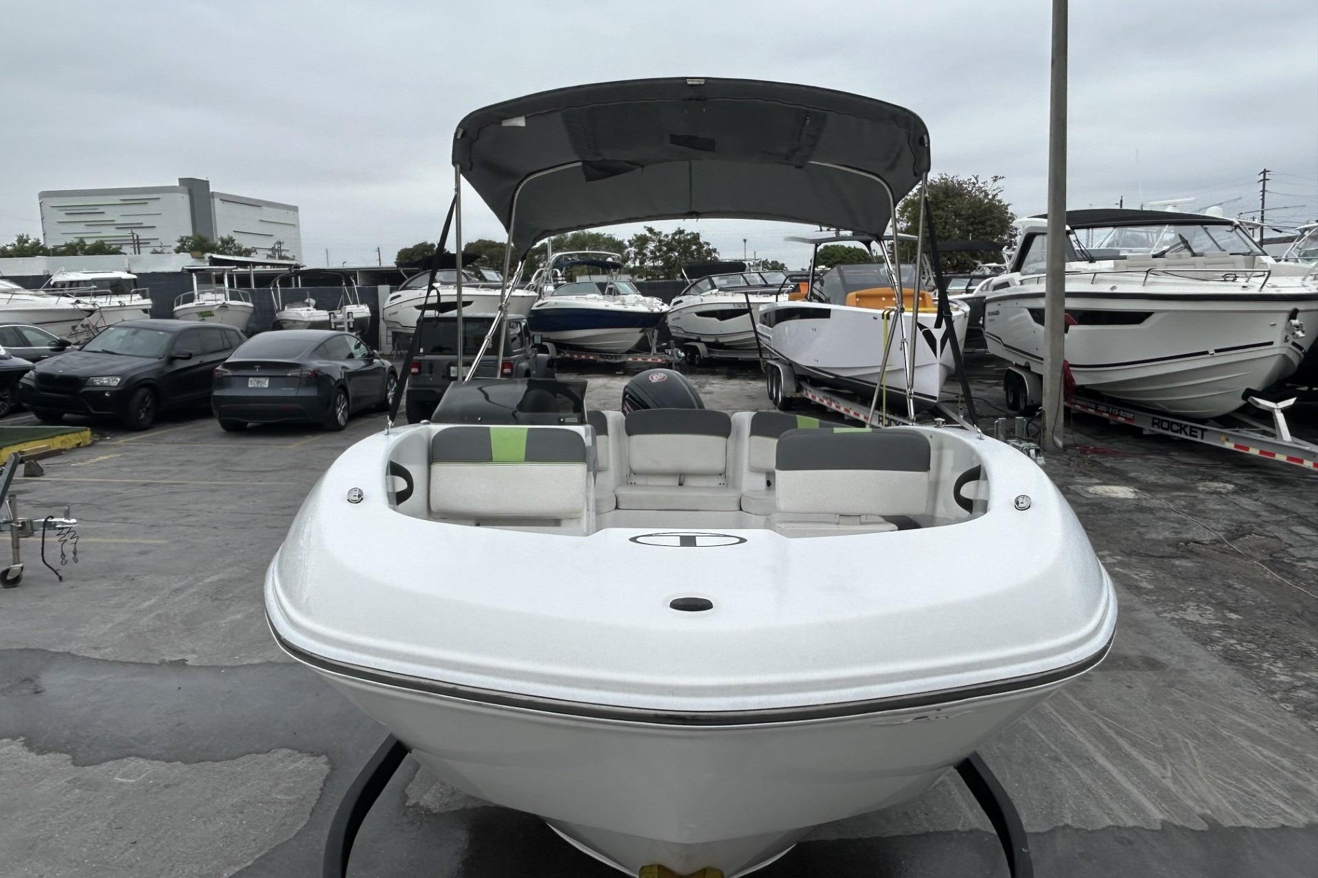 2022 Tahoe T18 boat with canopy in a marina, surrounded by other boats and cars.