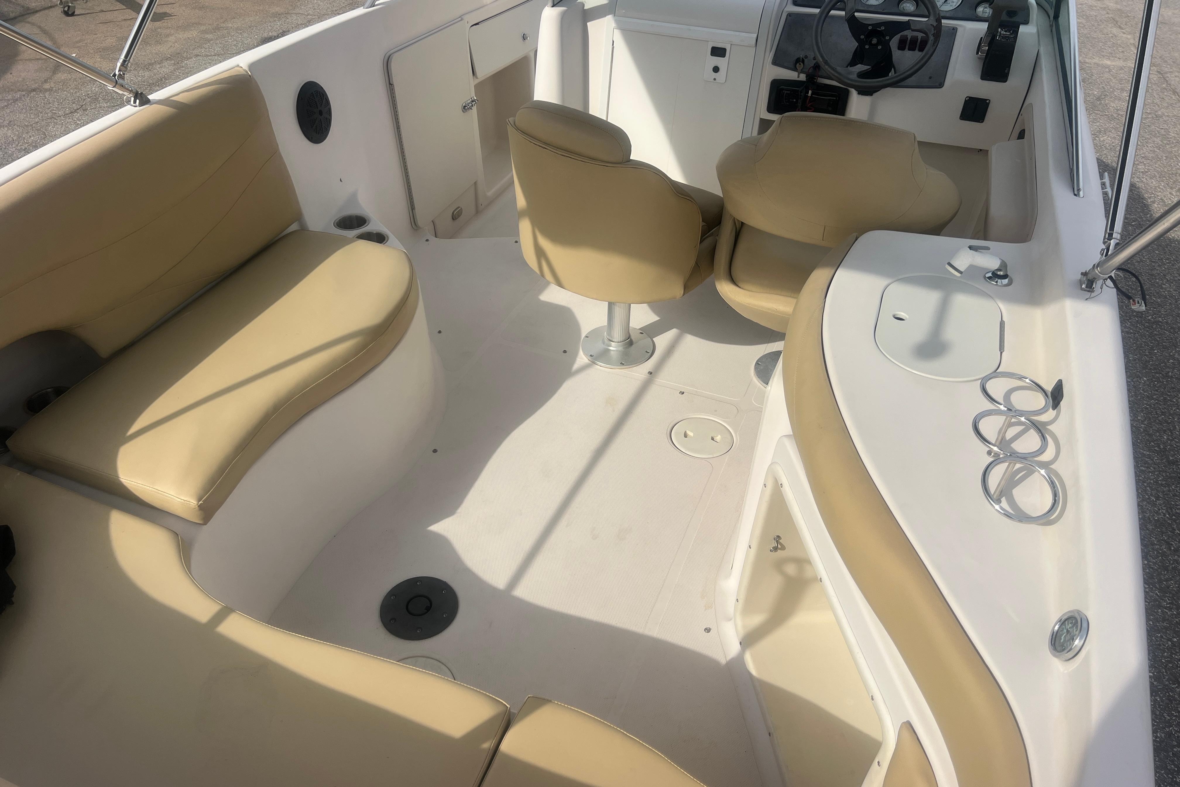 Interior of a 2002 Hurricane SunDeck 260 OB boat with beige seating and steering console.