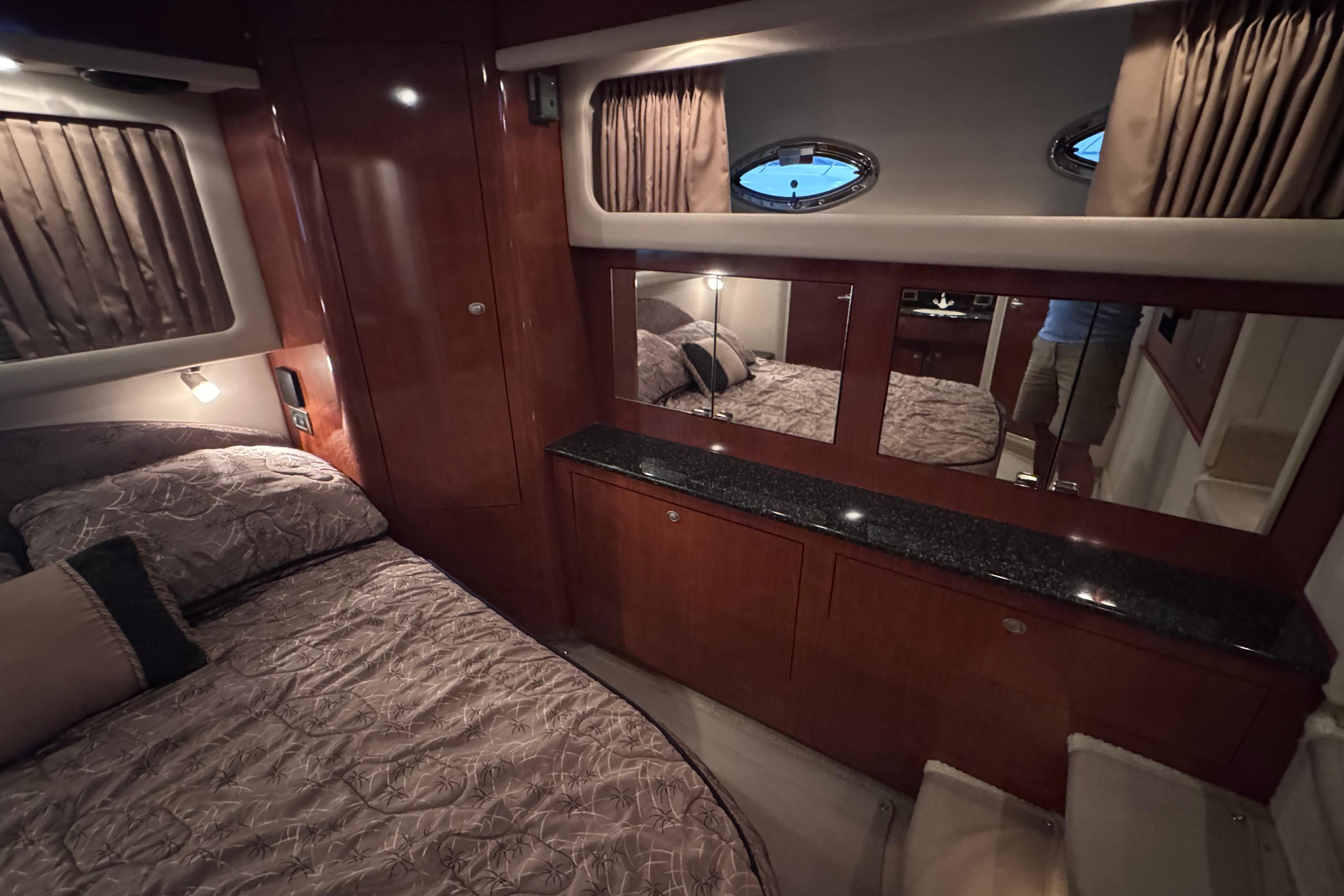 Luxurious 2004 Sea Ray 390 Motor Yacht cabin with elegant wood finishes and cozy bedding.