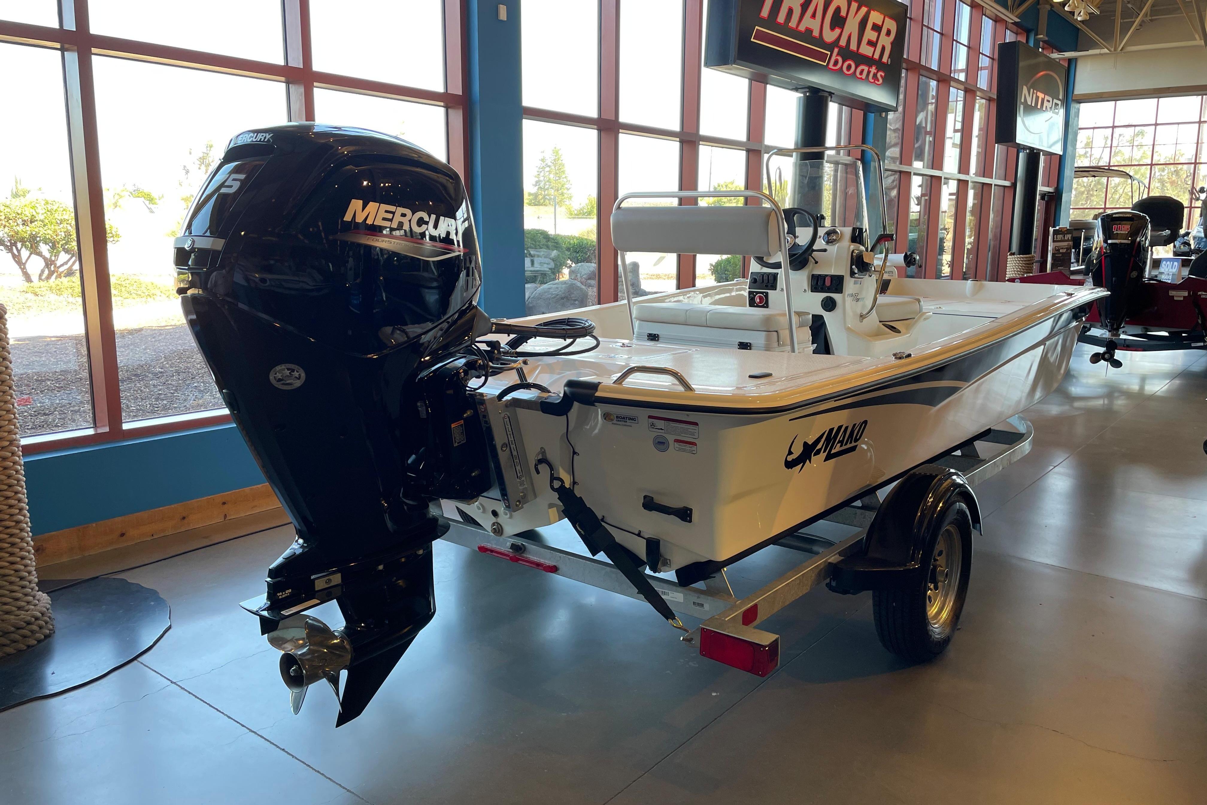 2026 Mako Pro Skiff 17 CC boat with Mercury engine displayed indoors.