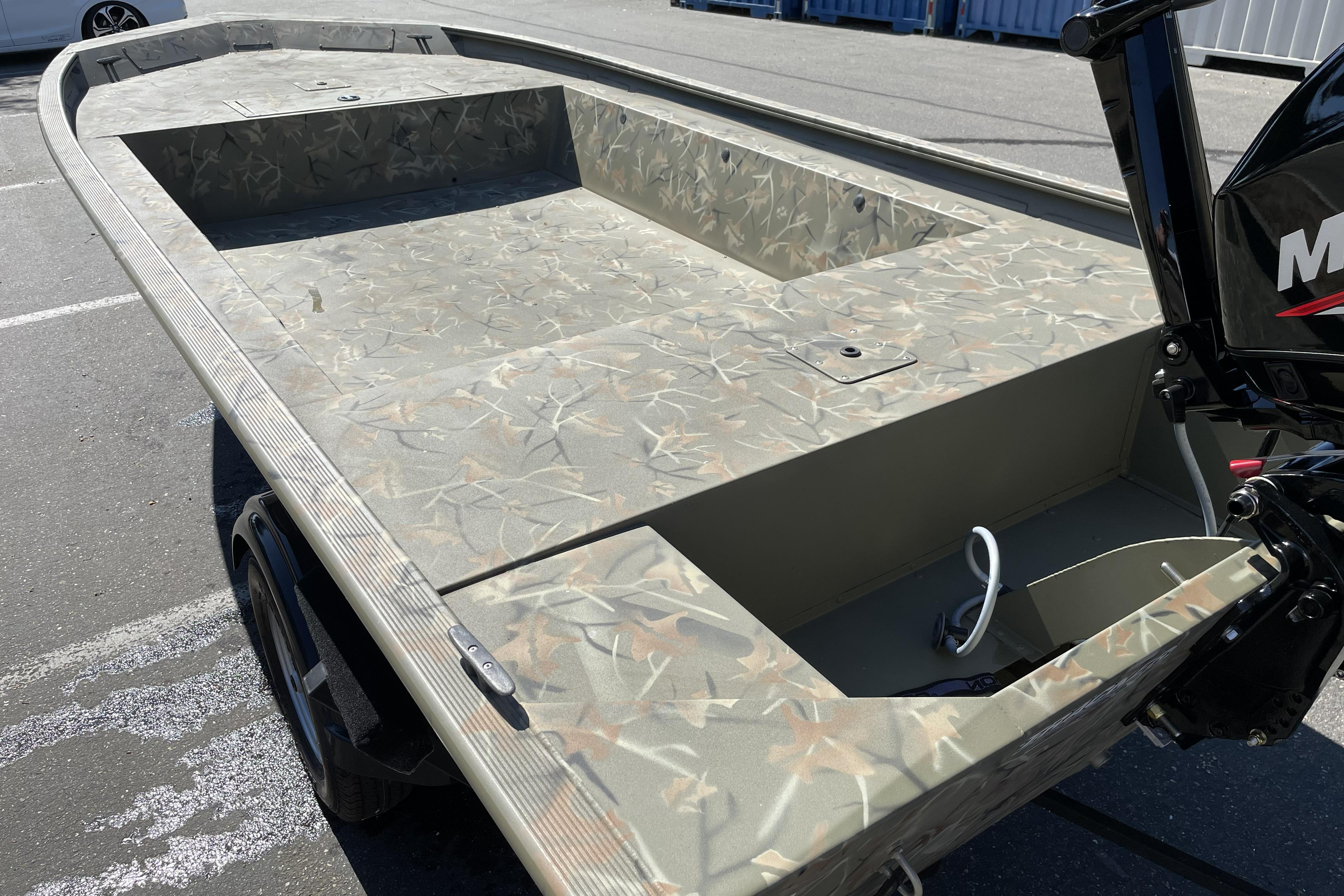 2025 Tracker Grizzly 1754 Jon boat with camouflage design, parked outdoors.