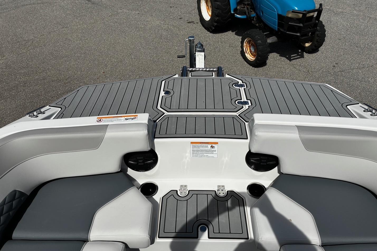 2026 Starcraft SVX 191 OB boat interior with gray seating and deck, parked near a blue tractor.