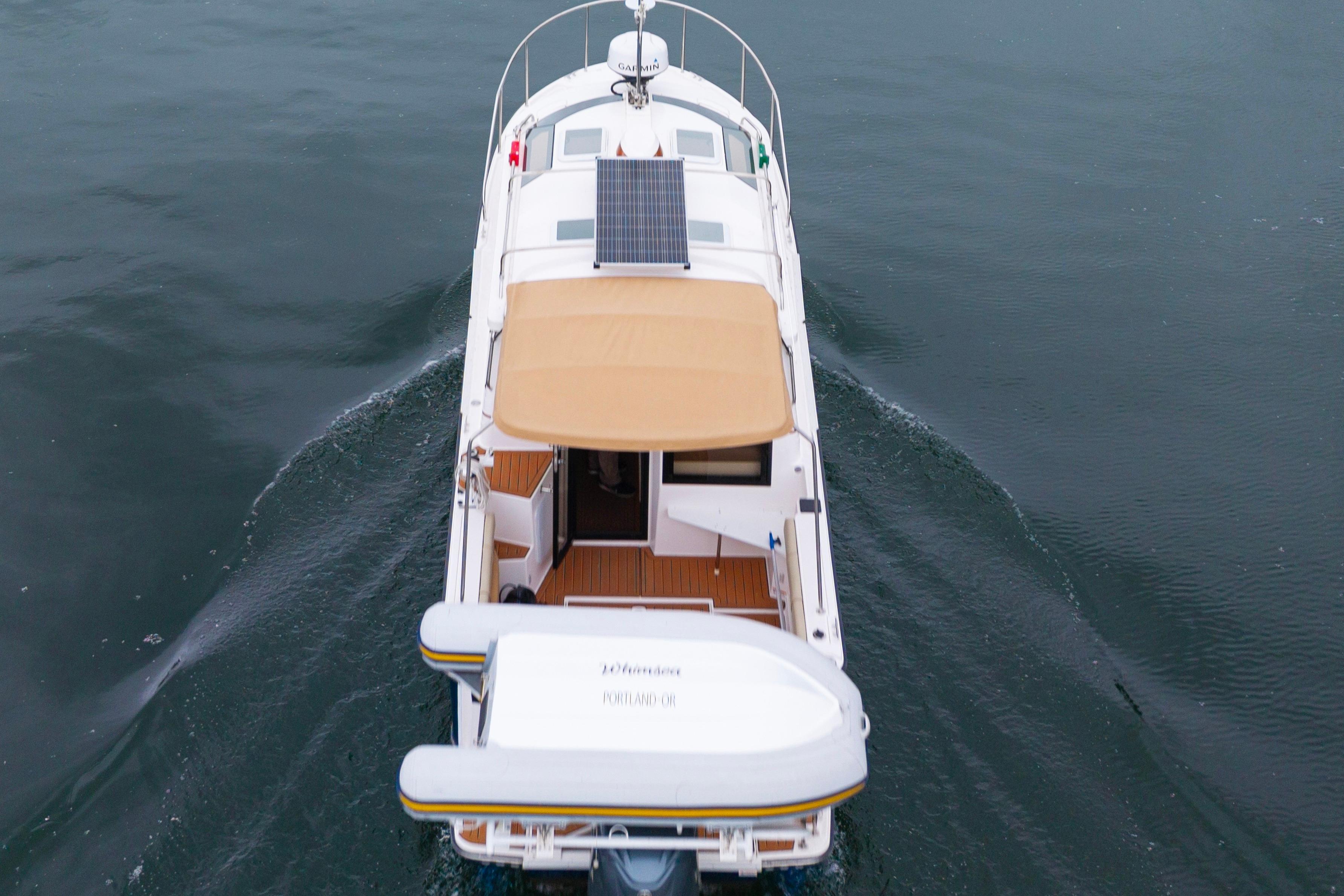 2022 Ranger Tugs R-27 cruising on water, featuring solar panel and beige canopy.