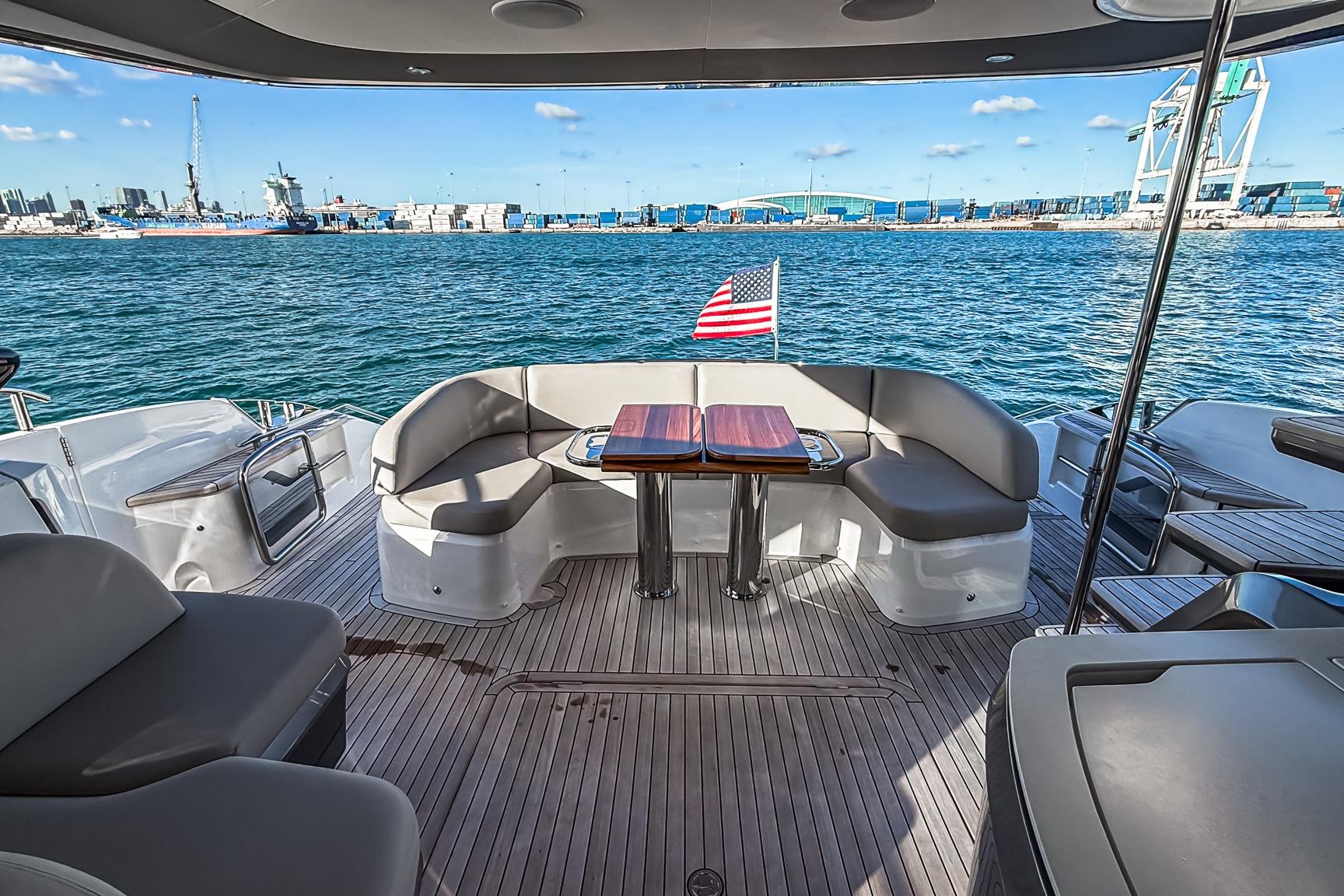Luxurious 2026 Princess S65 Sportbridge yacht deck with seating, ocean view, and American flag.