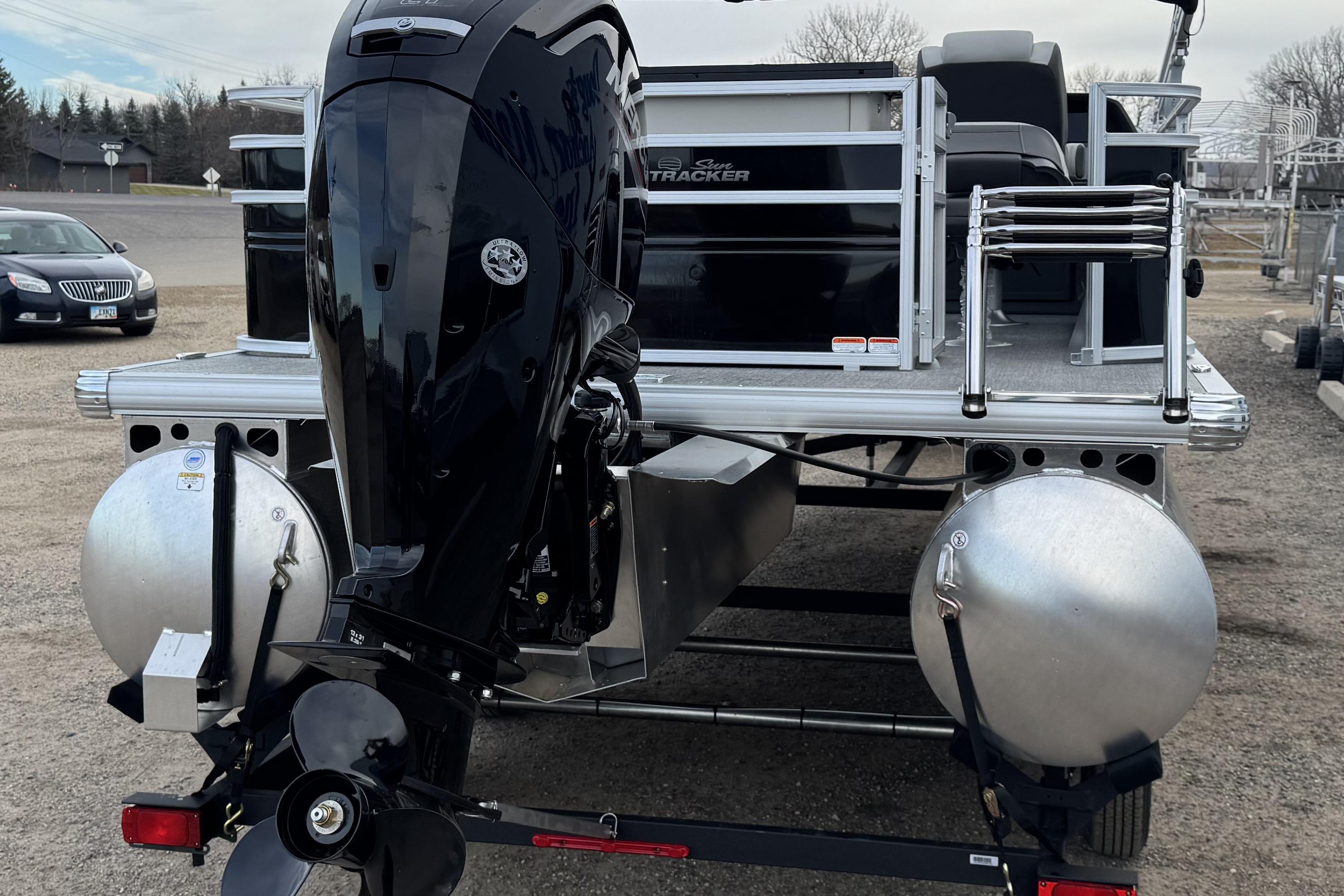 2026 Sun Tracker Fishin' Barge 22 DLX pontoon boat with outboard motor, rear view.