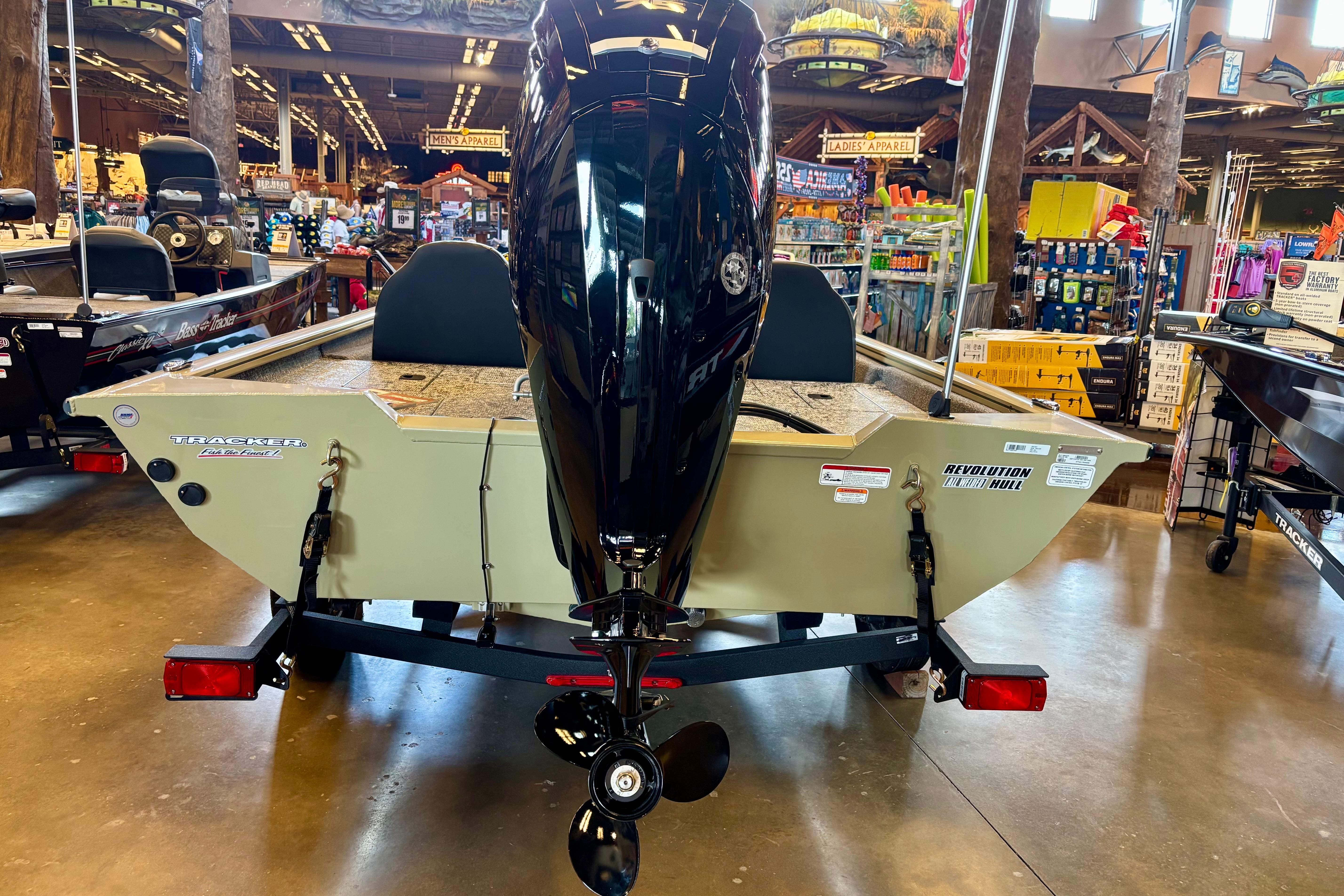 2026 Tracker Pro Team 175 boat displayed indoors, featuring a powerful outboard motor.