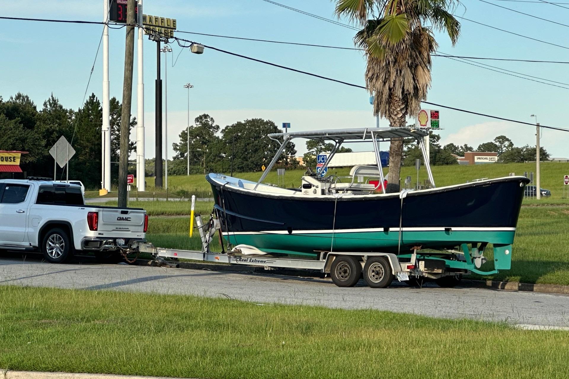 A 1997 Ocean Technical Services boat on a trailer, towed by a GMC truck.