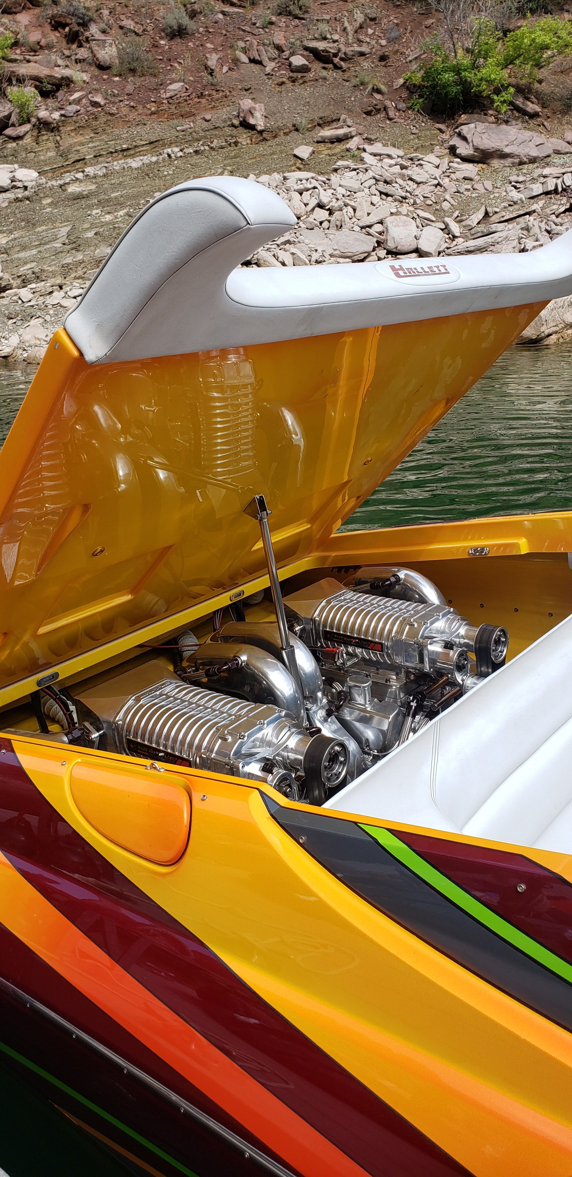 2009 Hallett 400T boat with open engine compartment by the water.
