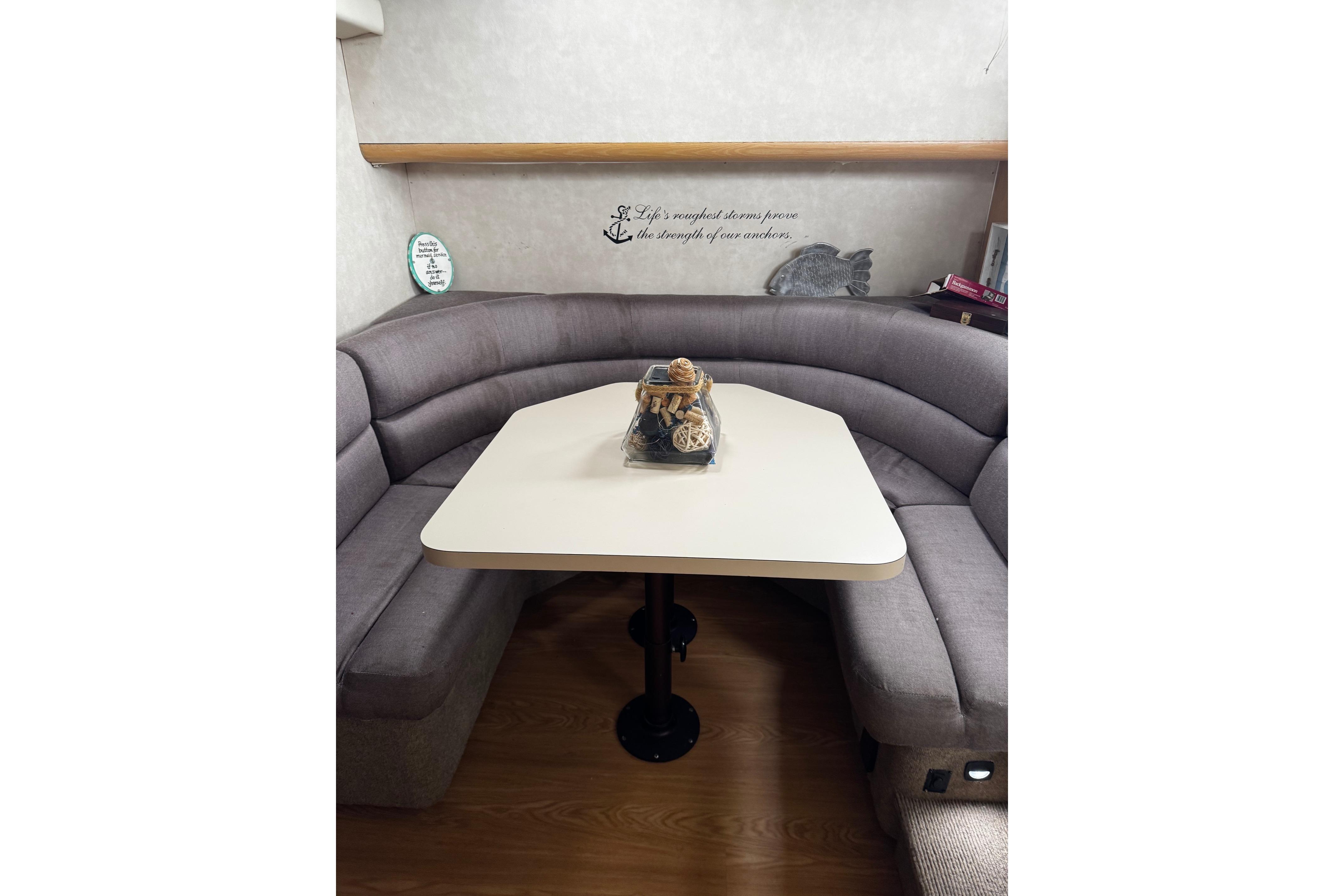 Cozy dining area in 1991 Silverton 46 Motor Yacht with curved seating and decorative centerpiece.