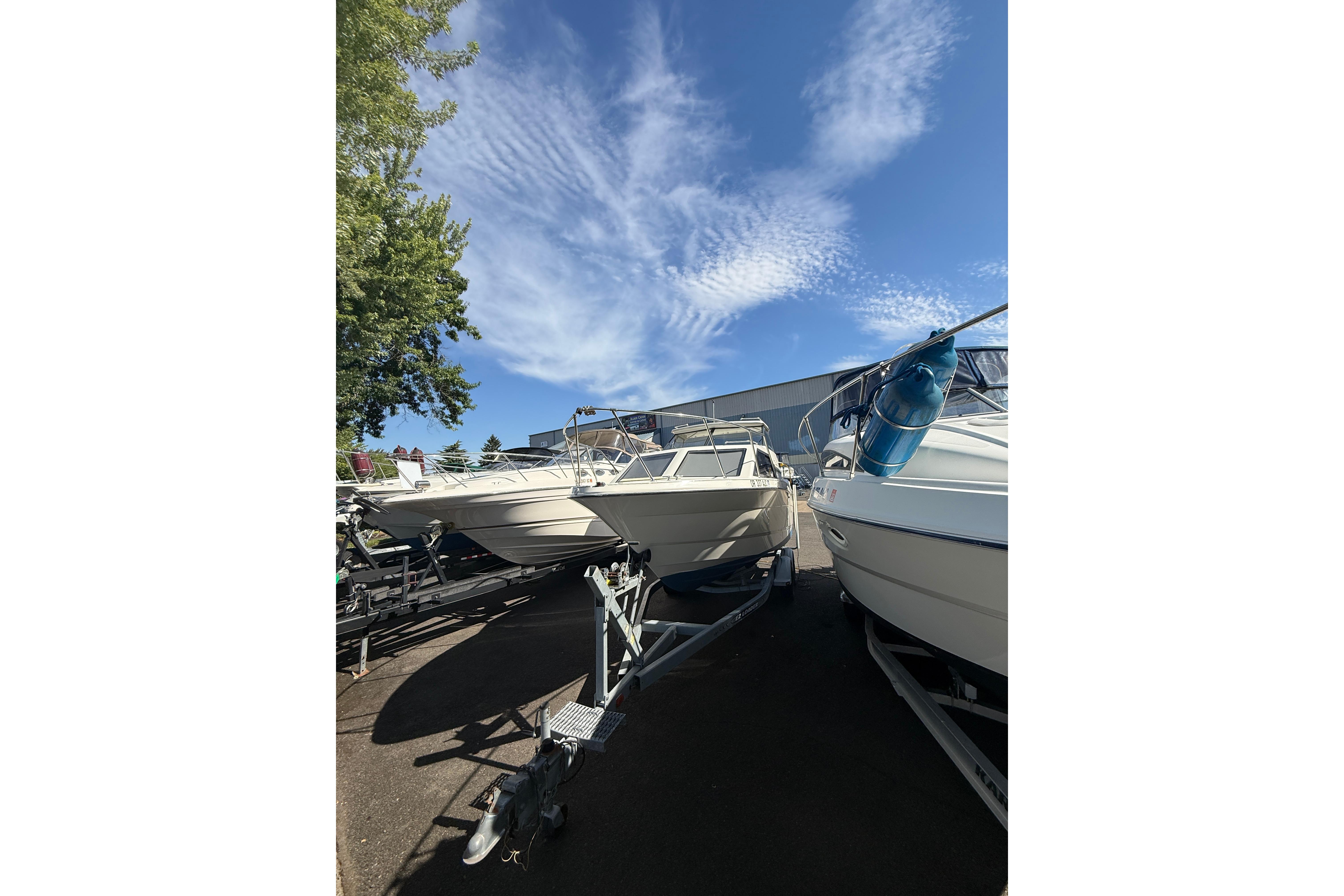 1997 Bayliner 2452 Ciera Express boats on trailers under a clear blue sky.