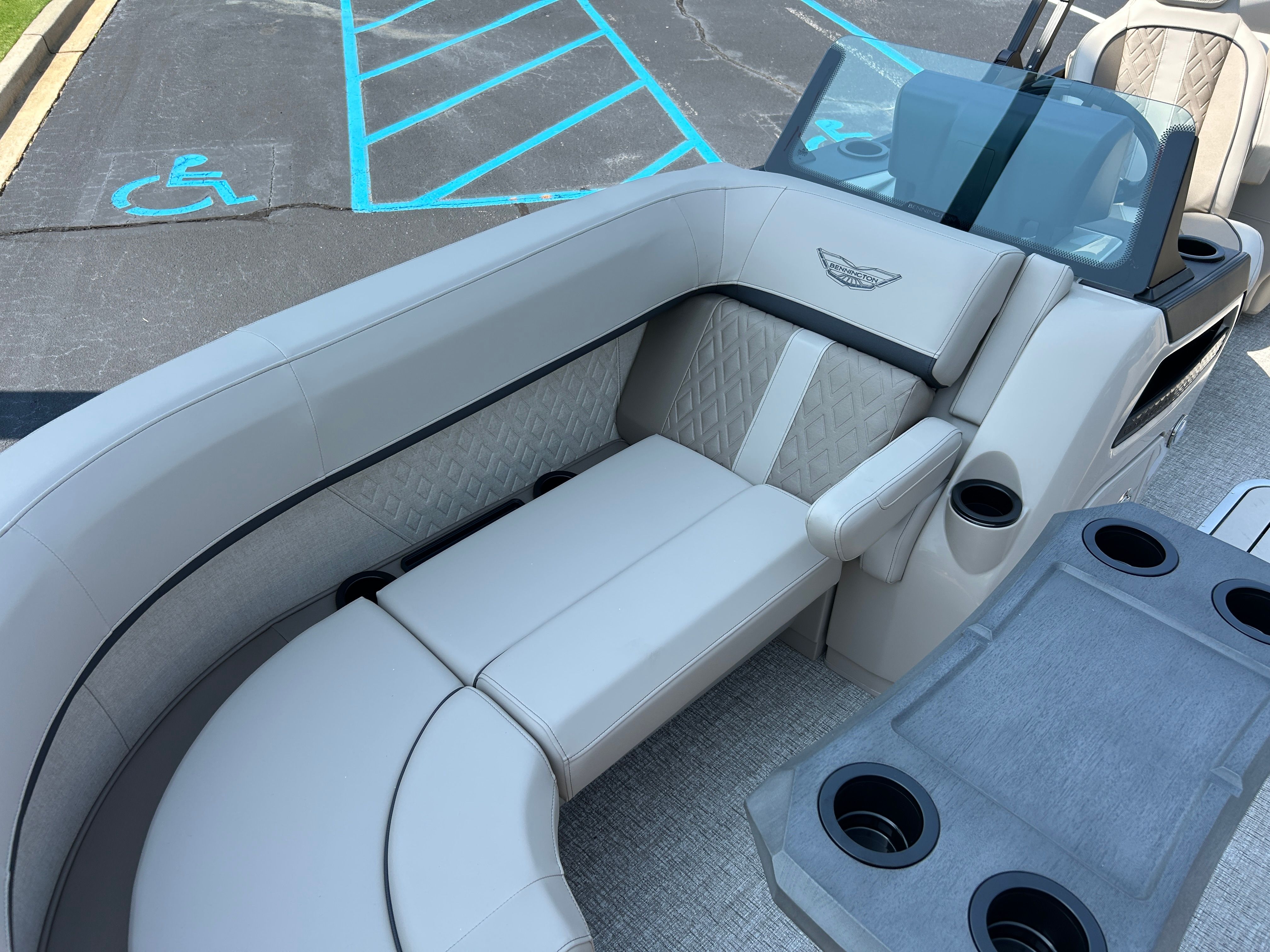 Luxurious seating area on a modern boat with gray upholstery and cup holders.
