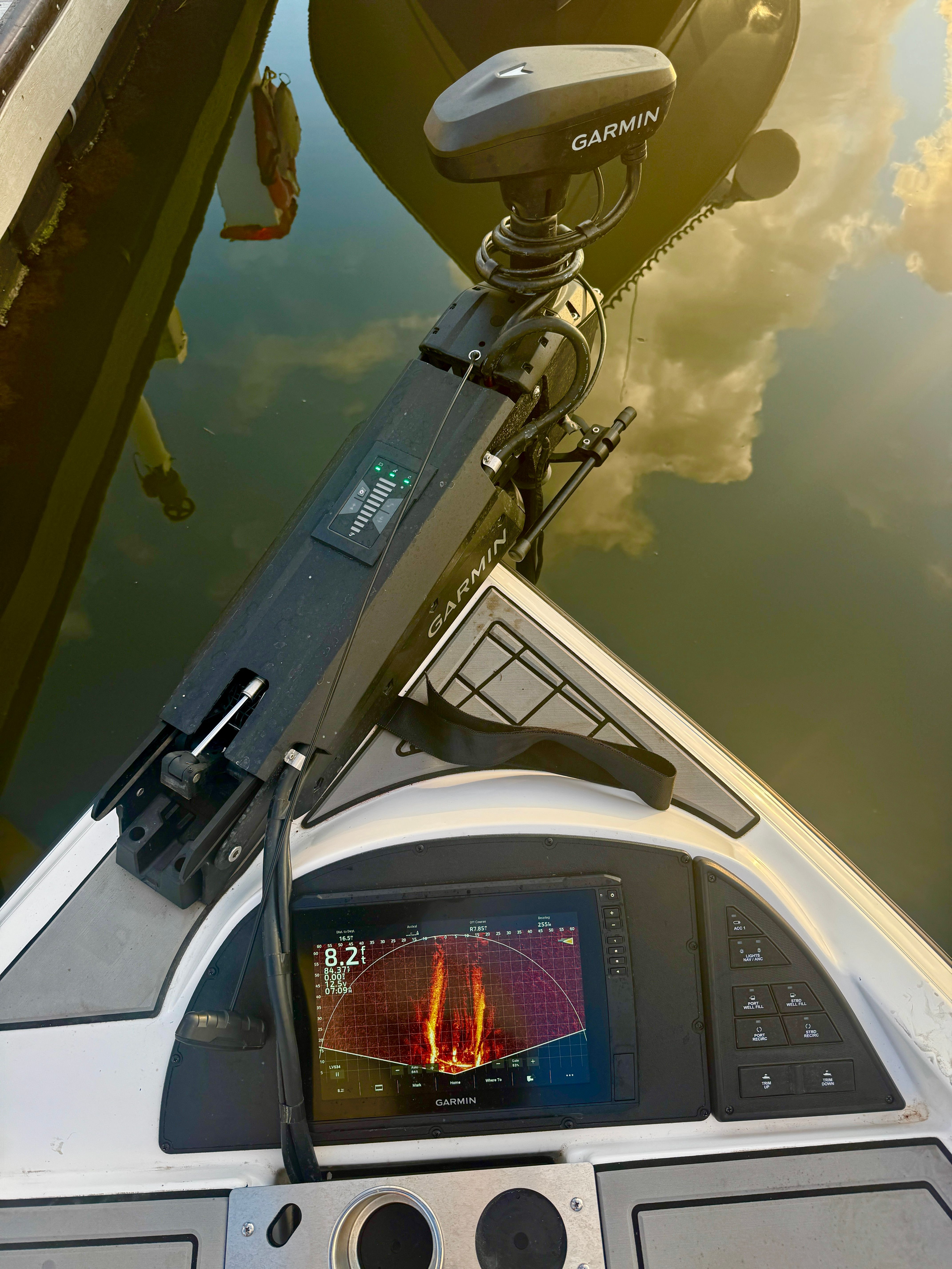 A modern boat with a Garmin fish finder and trolling motor on calm water.