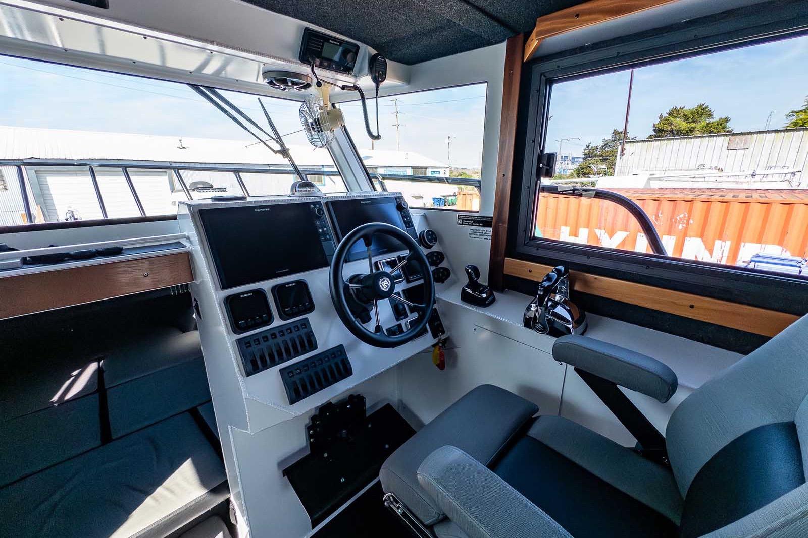 Interior of 2021 Wooldridge 33 Deep Water Explorer boat cockpit with steering wheel and controls.