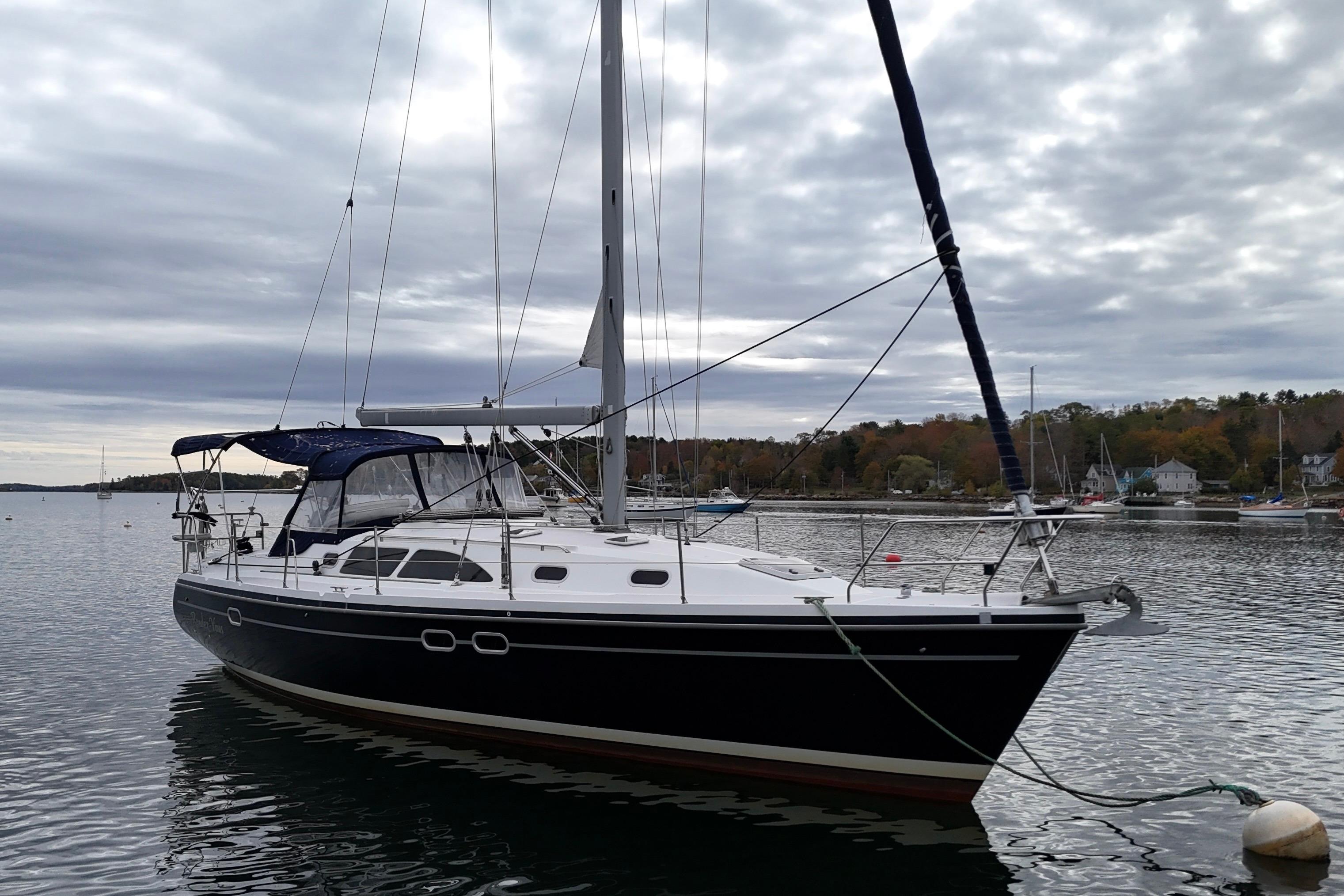 2003 Catalina 387 sailboat anchored on a calm lake under cloudy skies.