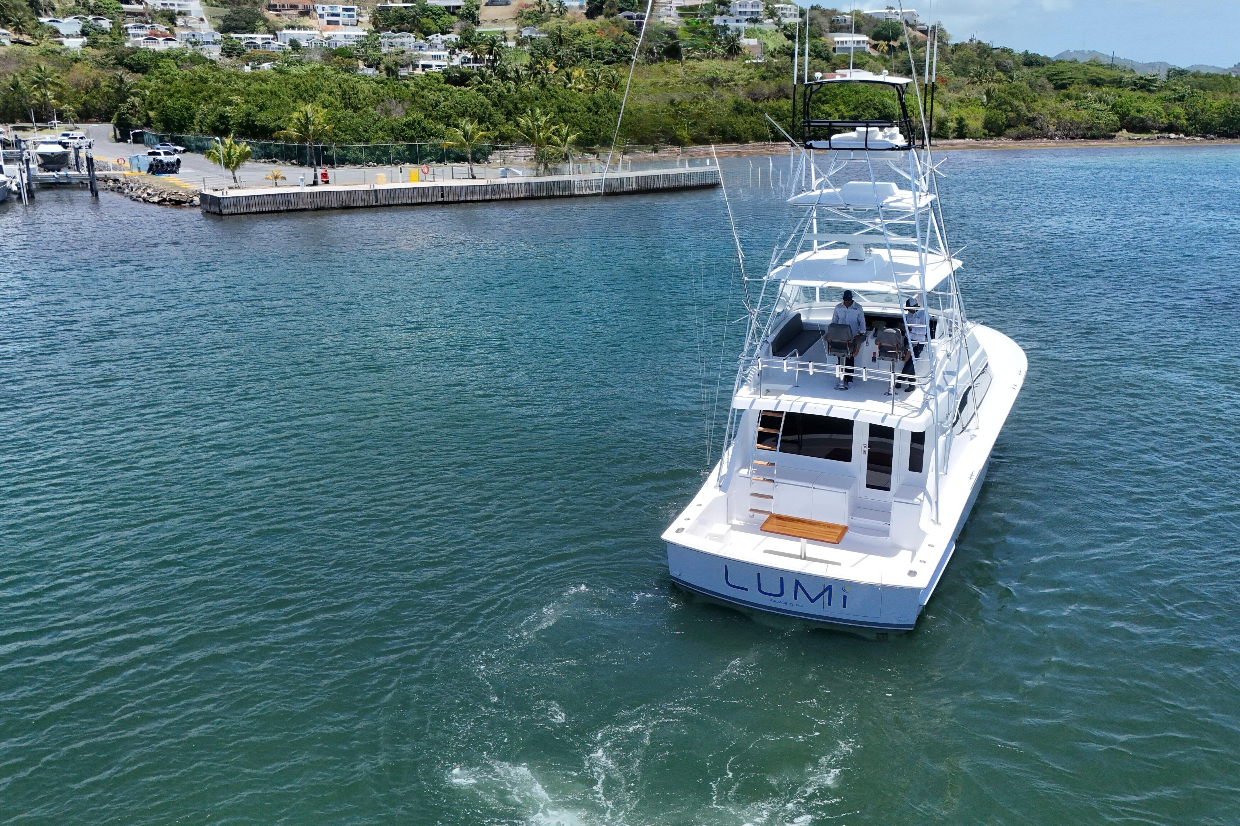 2003 Hatteras 54 Convertible yacht "LUMi" cruising in a scenic coastal area.