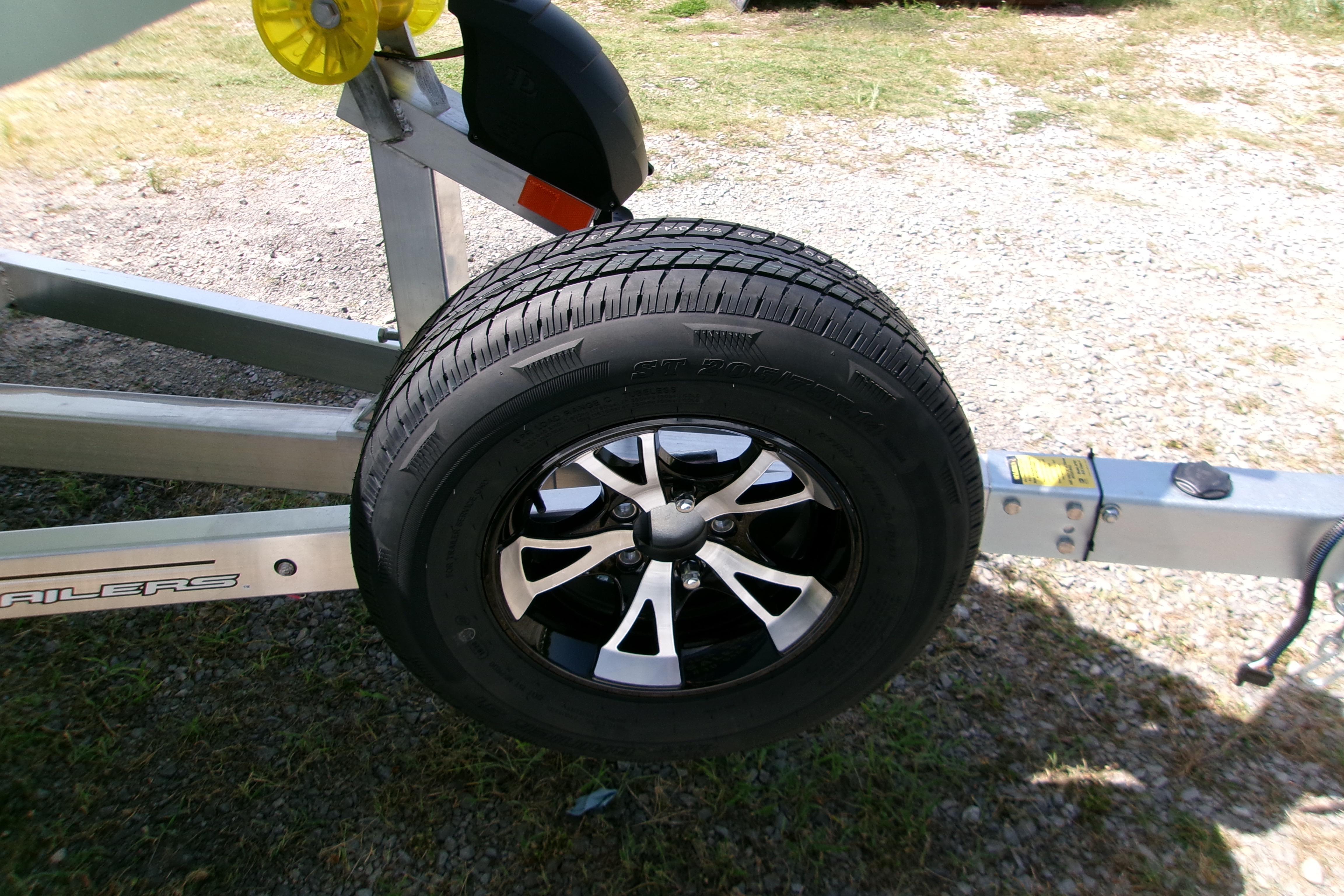 Trailer wheel of 2027 Xpress H22B Bay on gravel surface.
