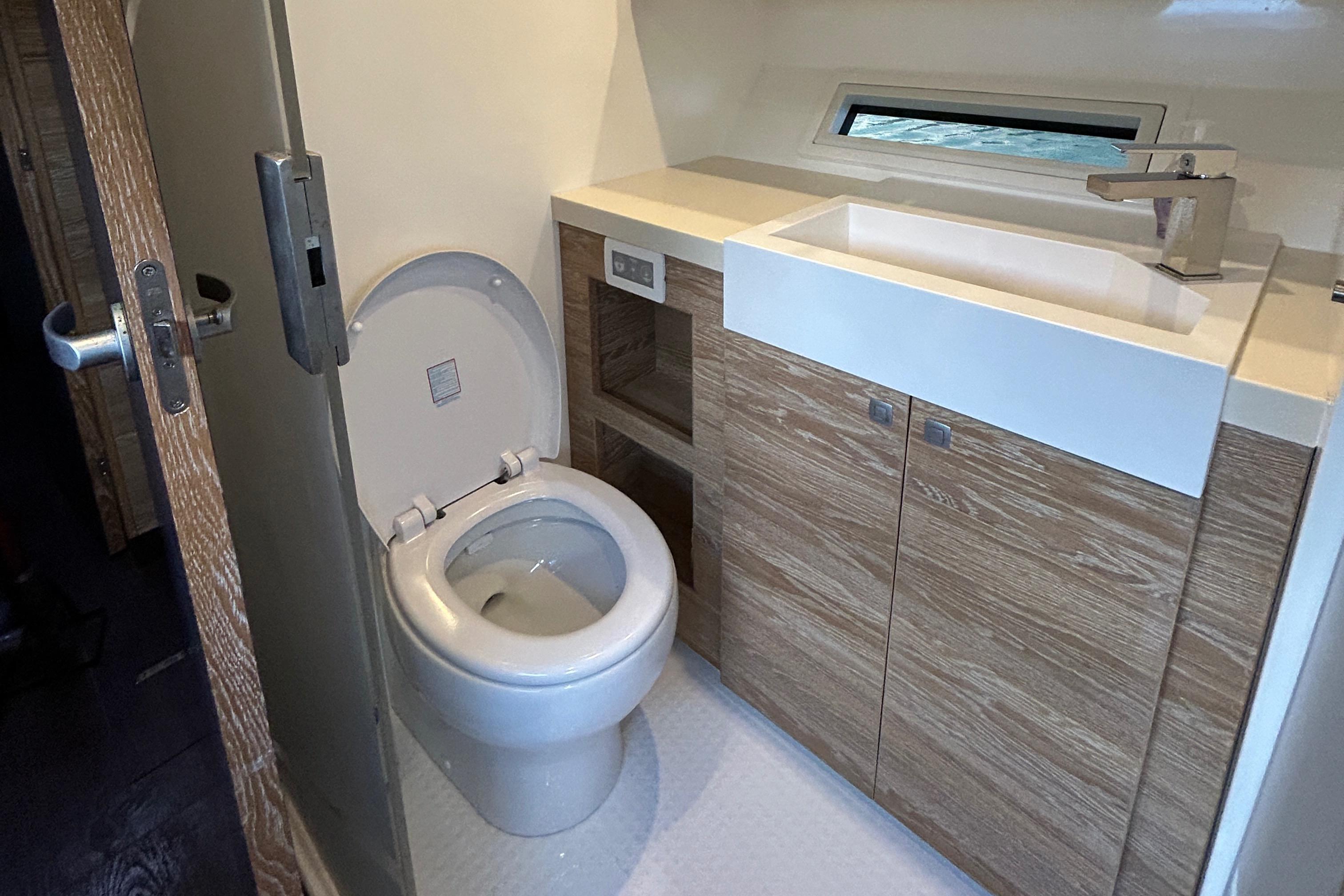 Modern bathroom in 2019 Xquisite Yachts X5 with wood cabinetry and sleek fixtures.
