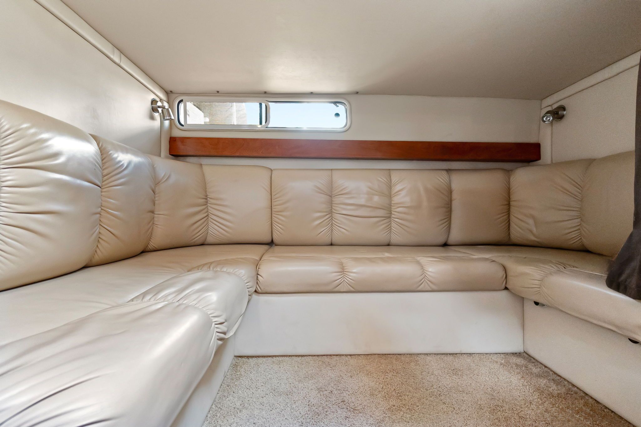 Interior of the 2007 Larson Cabrio 330 with beige leather sofa and small window.