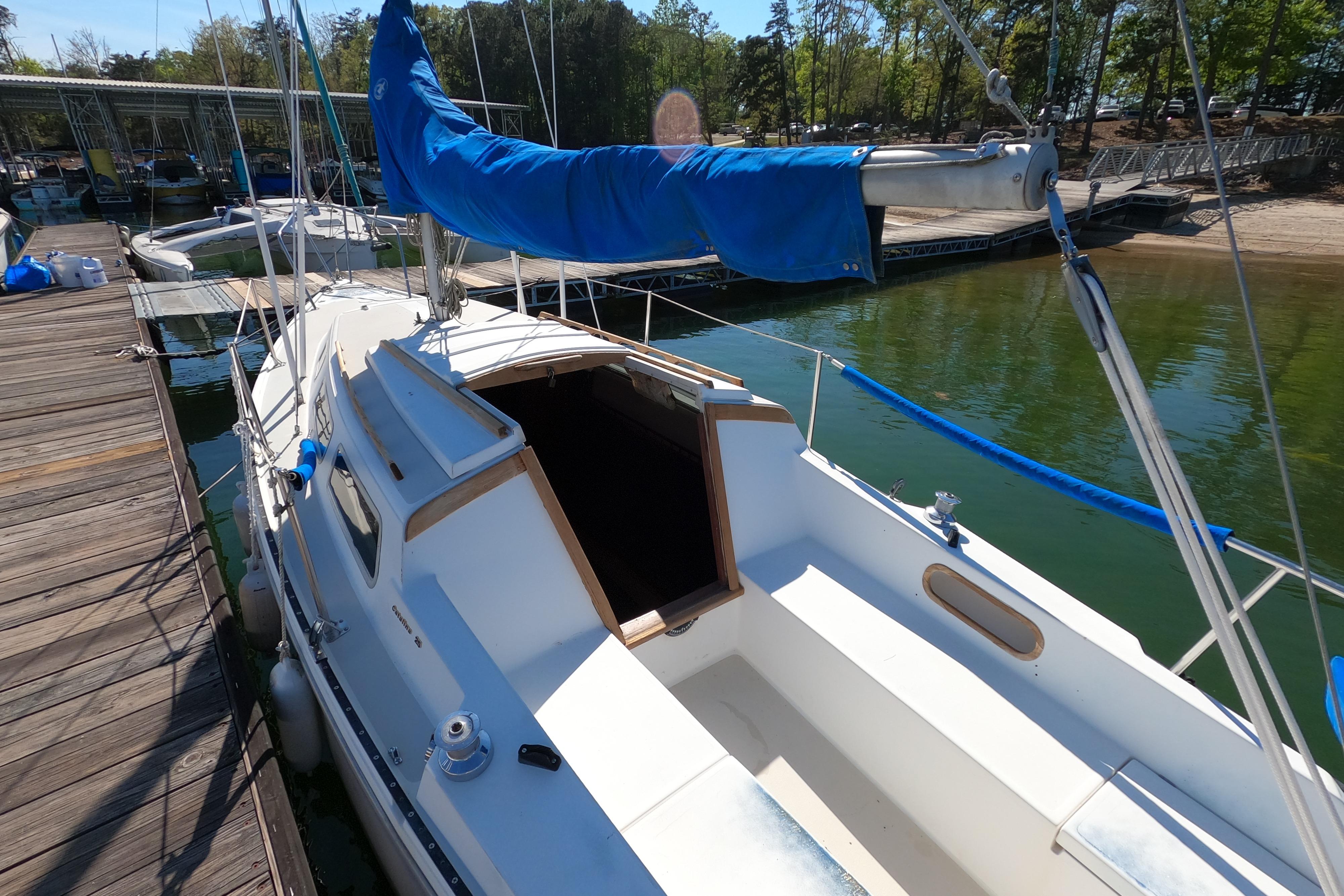 1983 Catalina 25 sailboat docked, featuring blue sail cover and open cabin entrance.