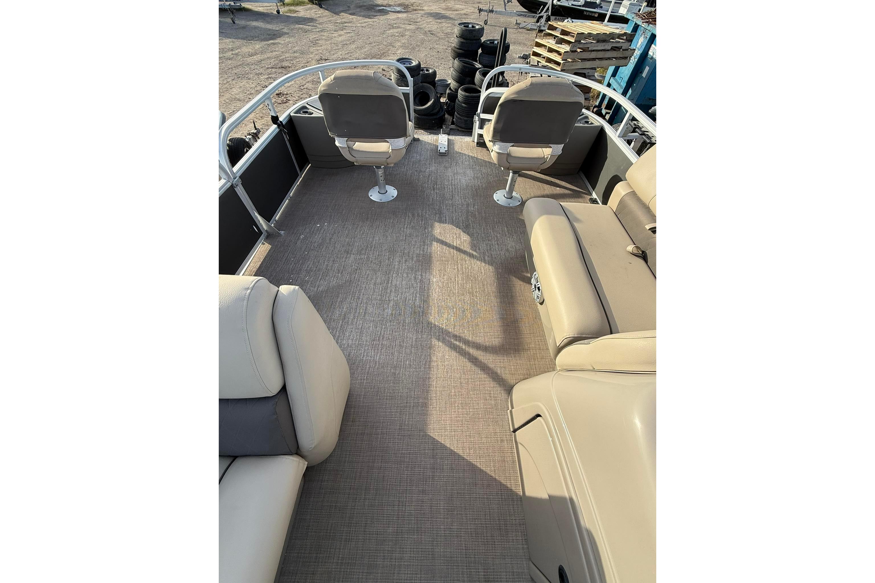 2023 Sun Tracker Fishin' Barge 22 DLX interior with beige seating and spacious deck.