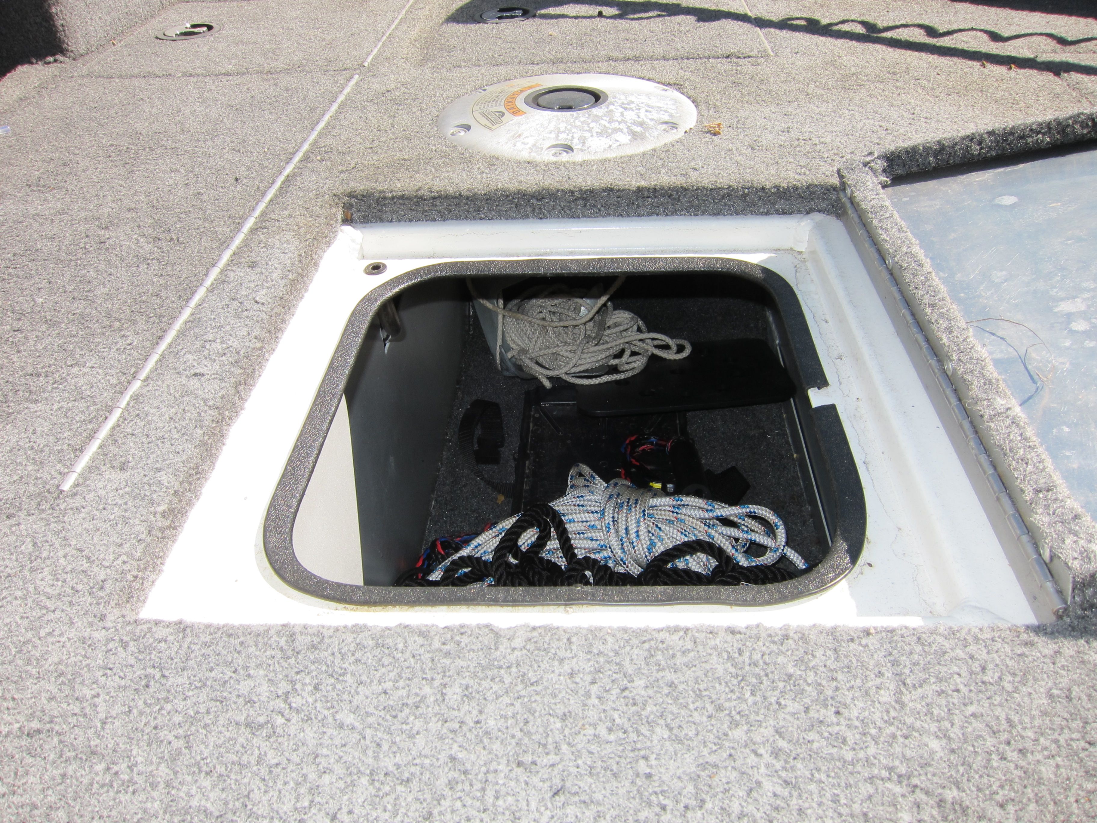 An open storage compartment on a boat with ropes and cables inside.