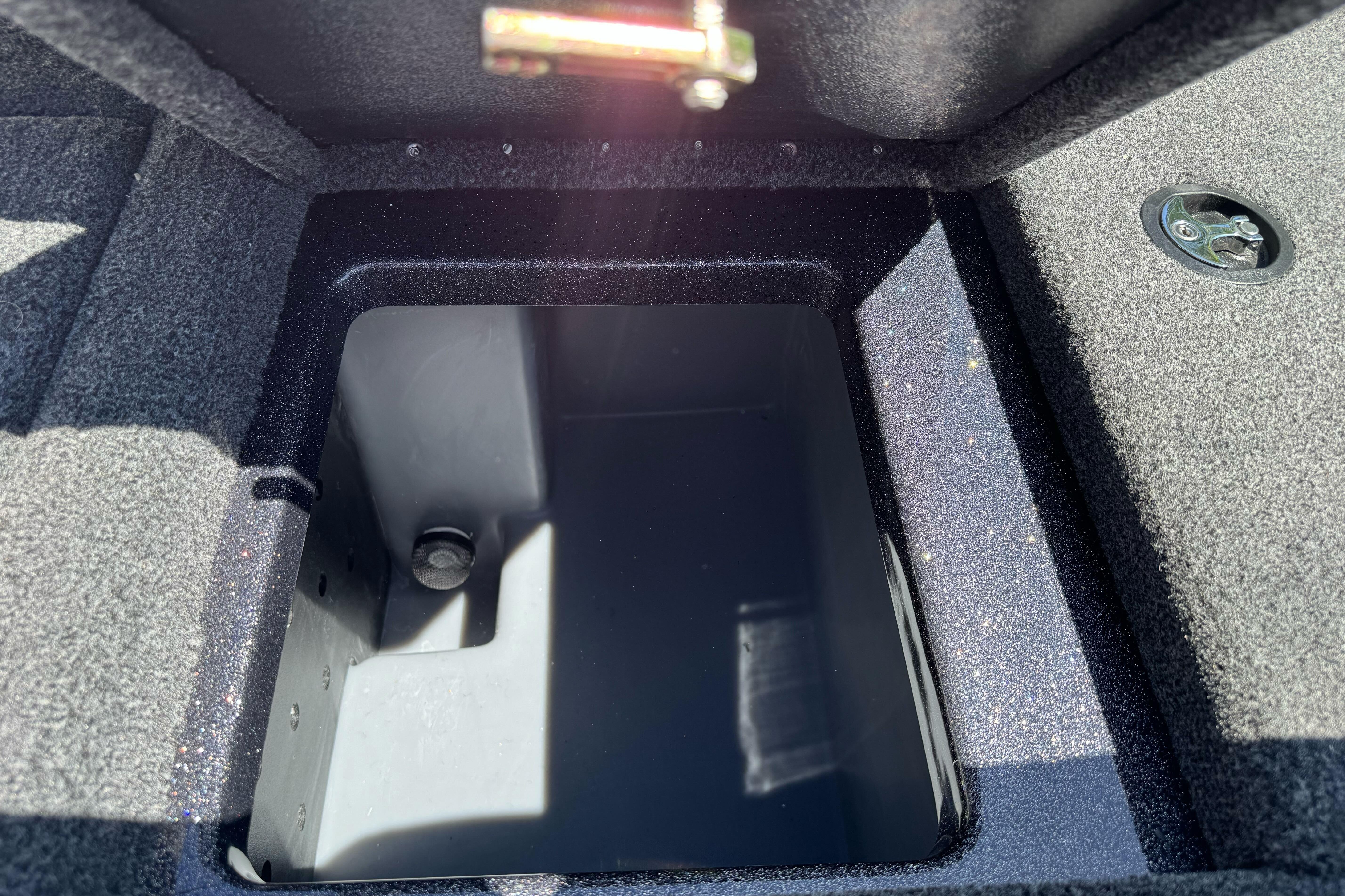 Open storage compartment in 2026 Triton 18 TrX boat, featuring carpeted interior.