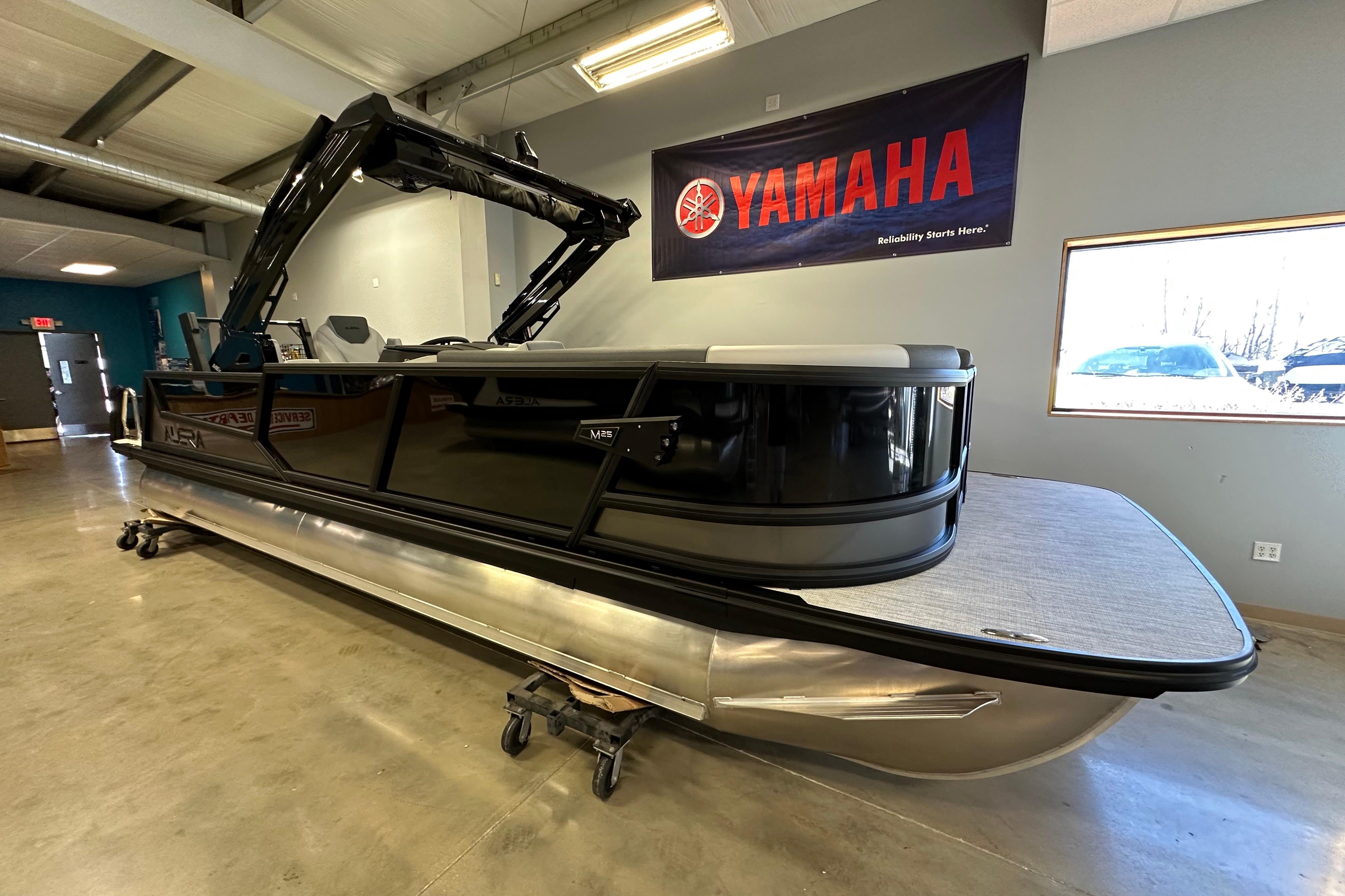 2026 Alera M25L pontoon boat displayed indoors with Yamaha banner.