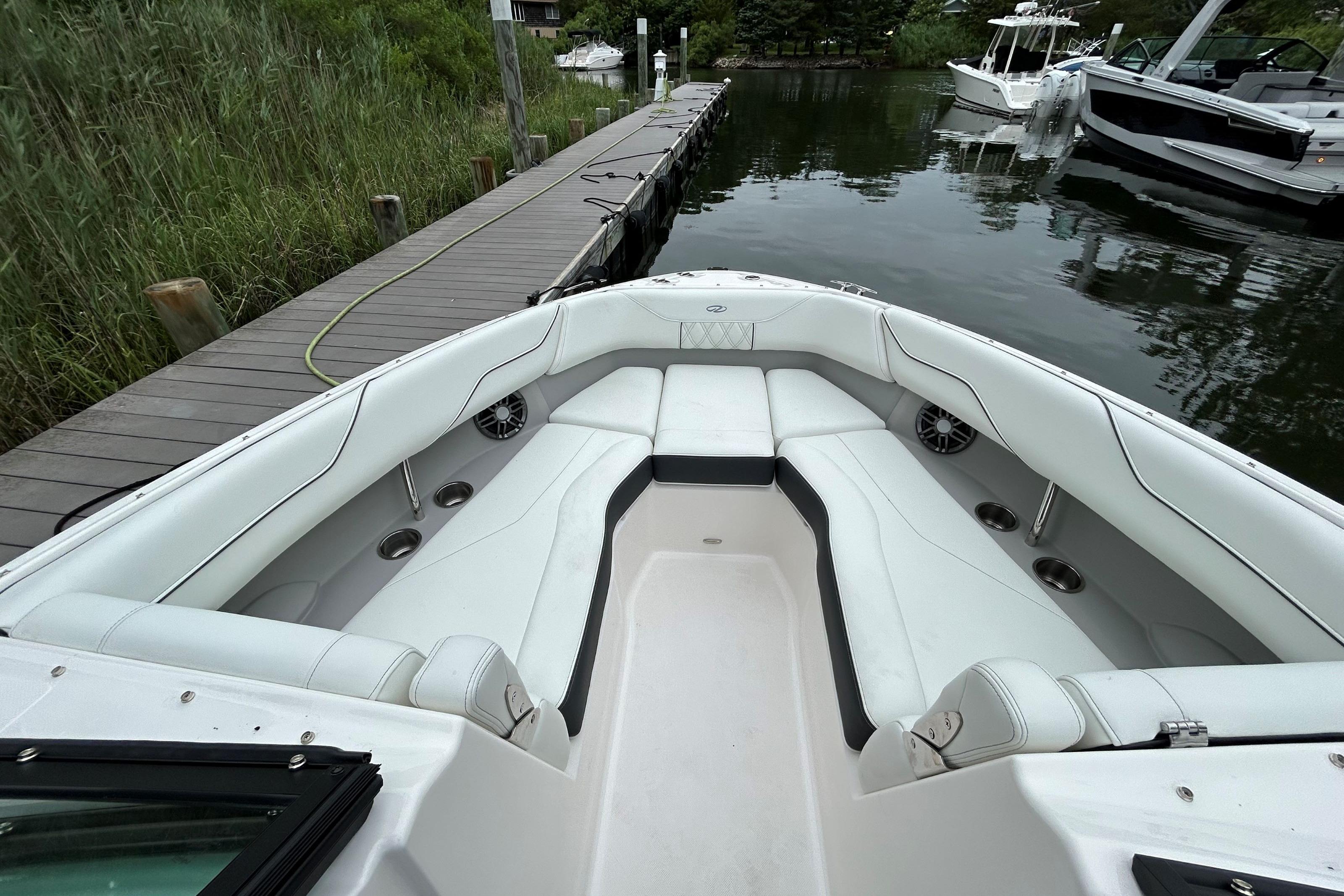 2022 Regal LX4 boat with spacious white seating, docked by a wooden pier.