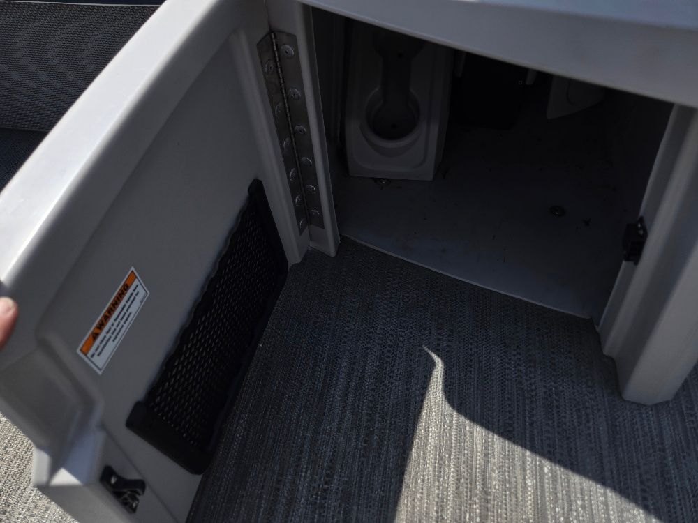 An open storage compartment with gray carpeting on a boat.