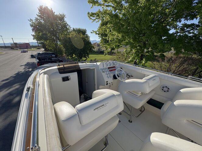 2002 Advantage Victory boat interior with white seating and control panel, parked near trees.