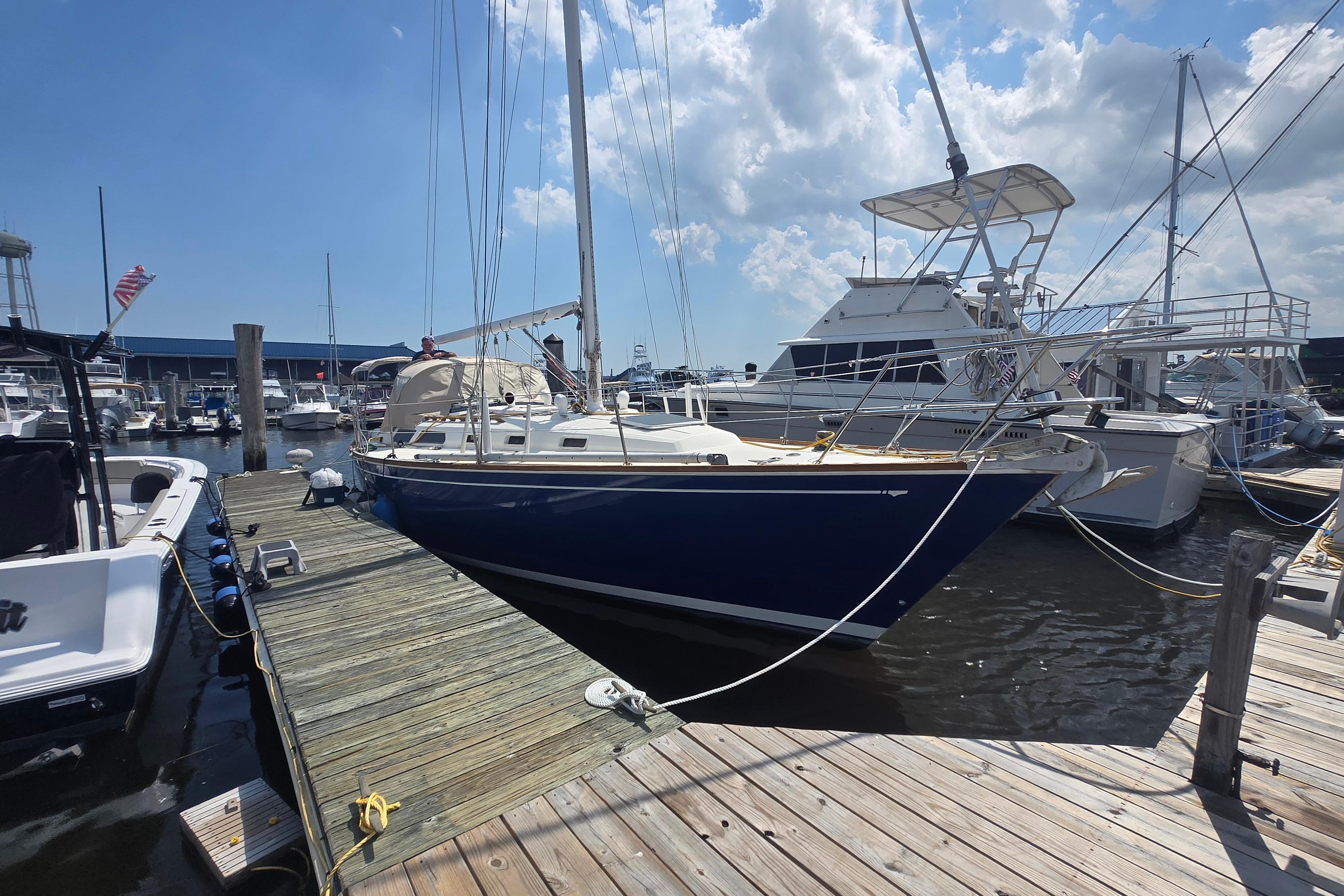1988 Sabre 38 sailboat docked at a marina under a partly cloudy sky.