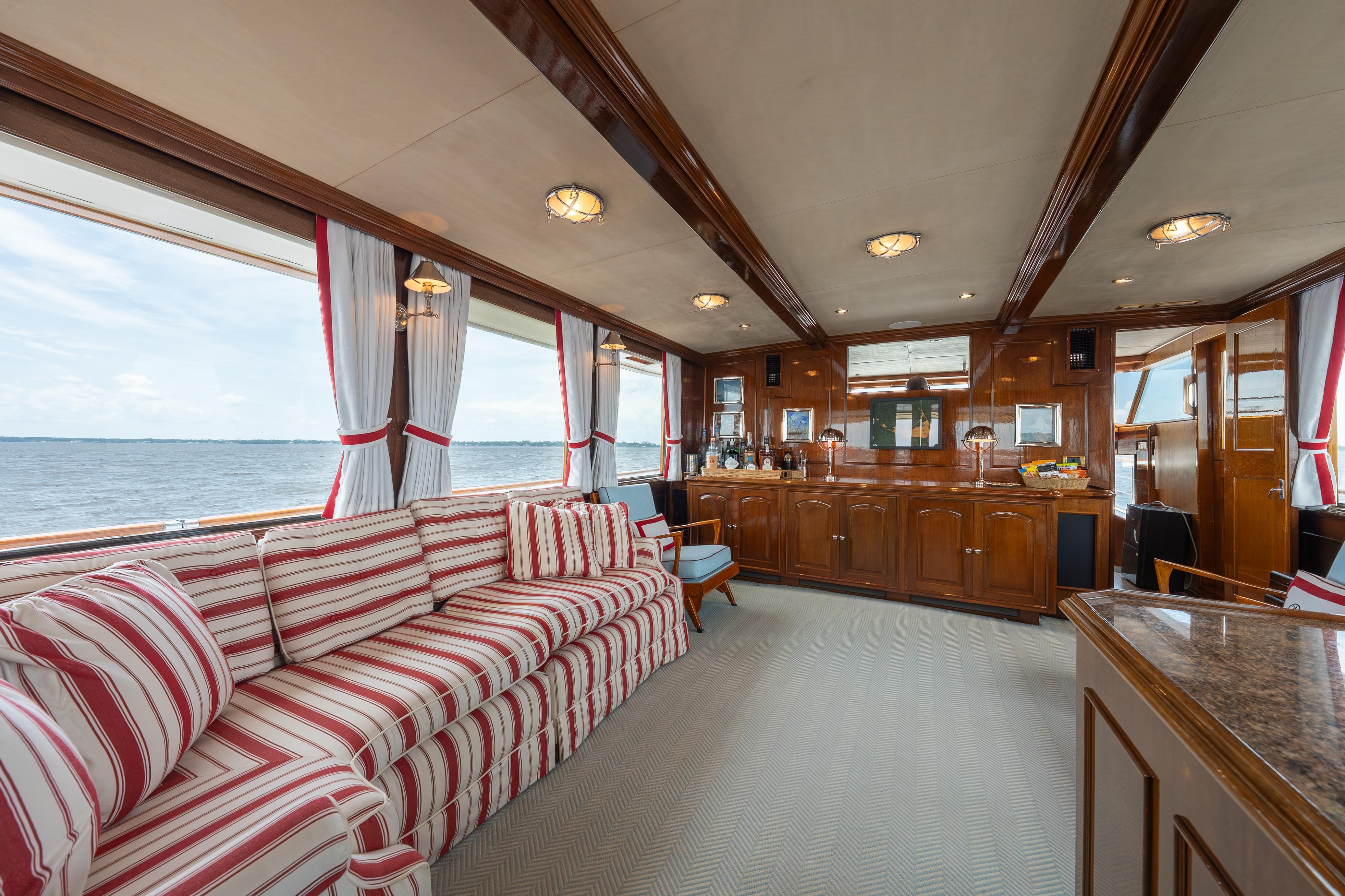 Luxurious 1963 Trumpy Classic yacht interior with striped seating and elegant wood paneling.