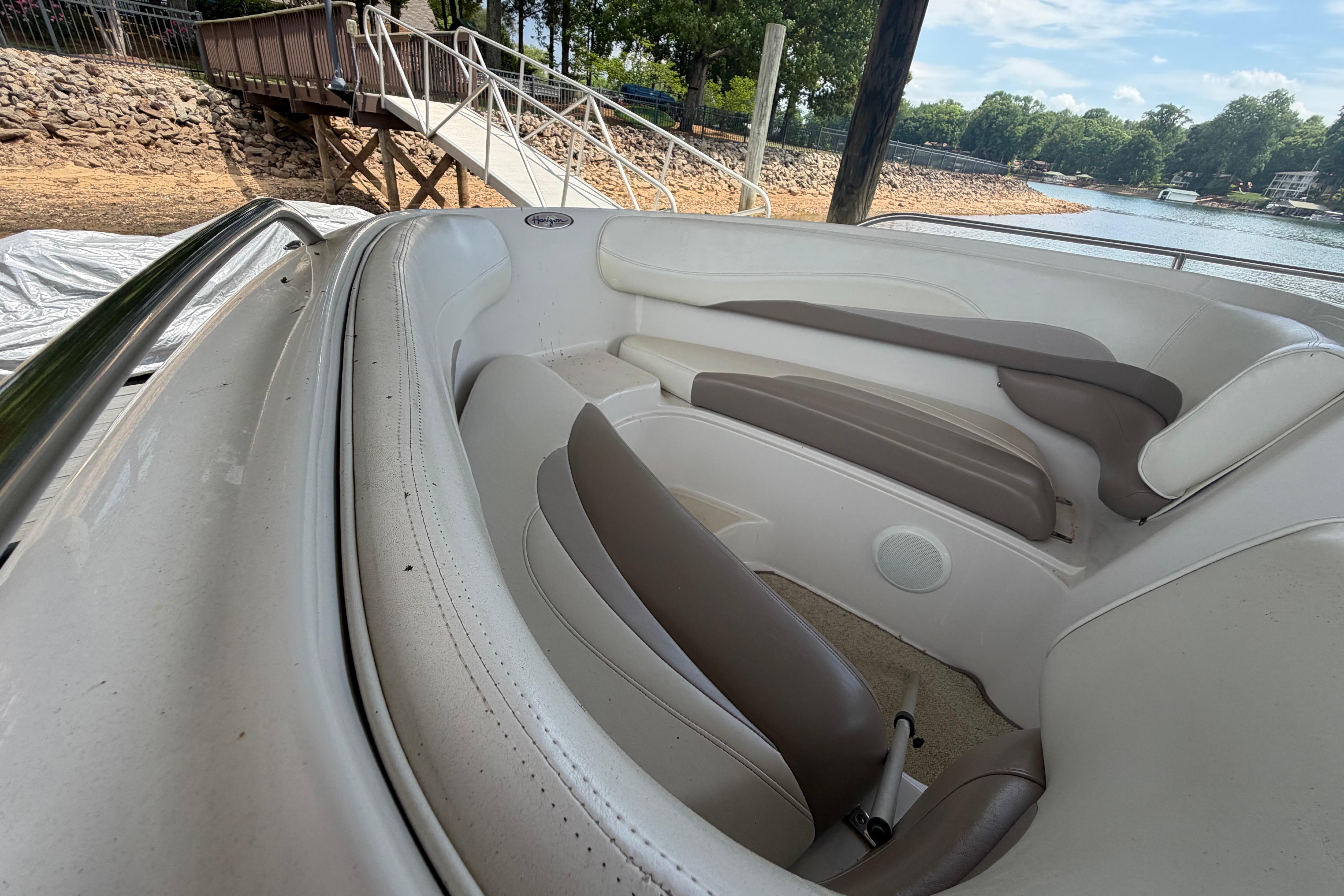 1998 Four Winns 220 Horizon boat interior with white and brown seating near a lakeside dock.