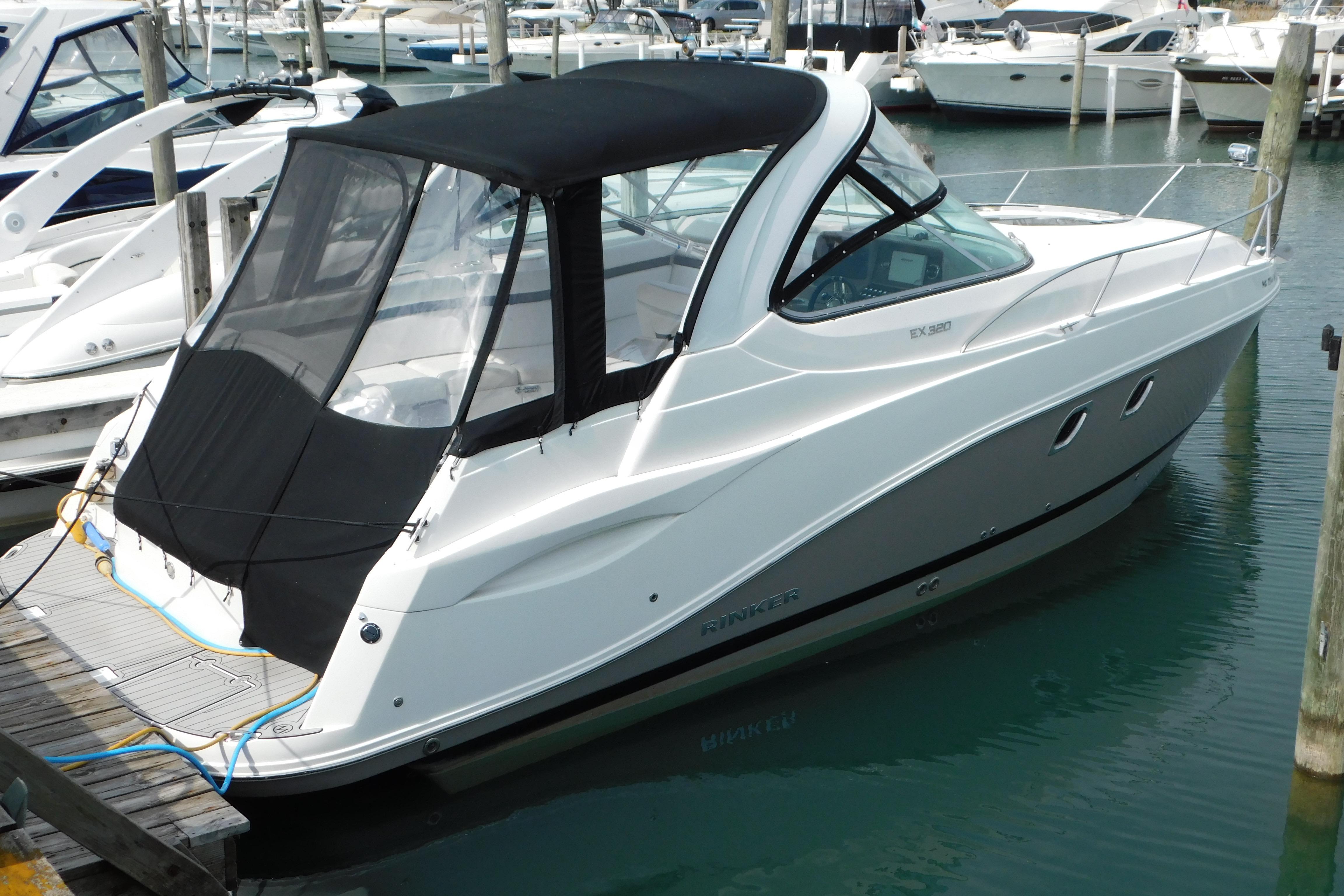 2017 Rinker EX 320 boat docked in marina, featuring sleek design and black canopy.