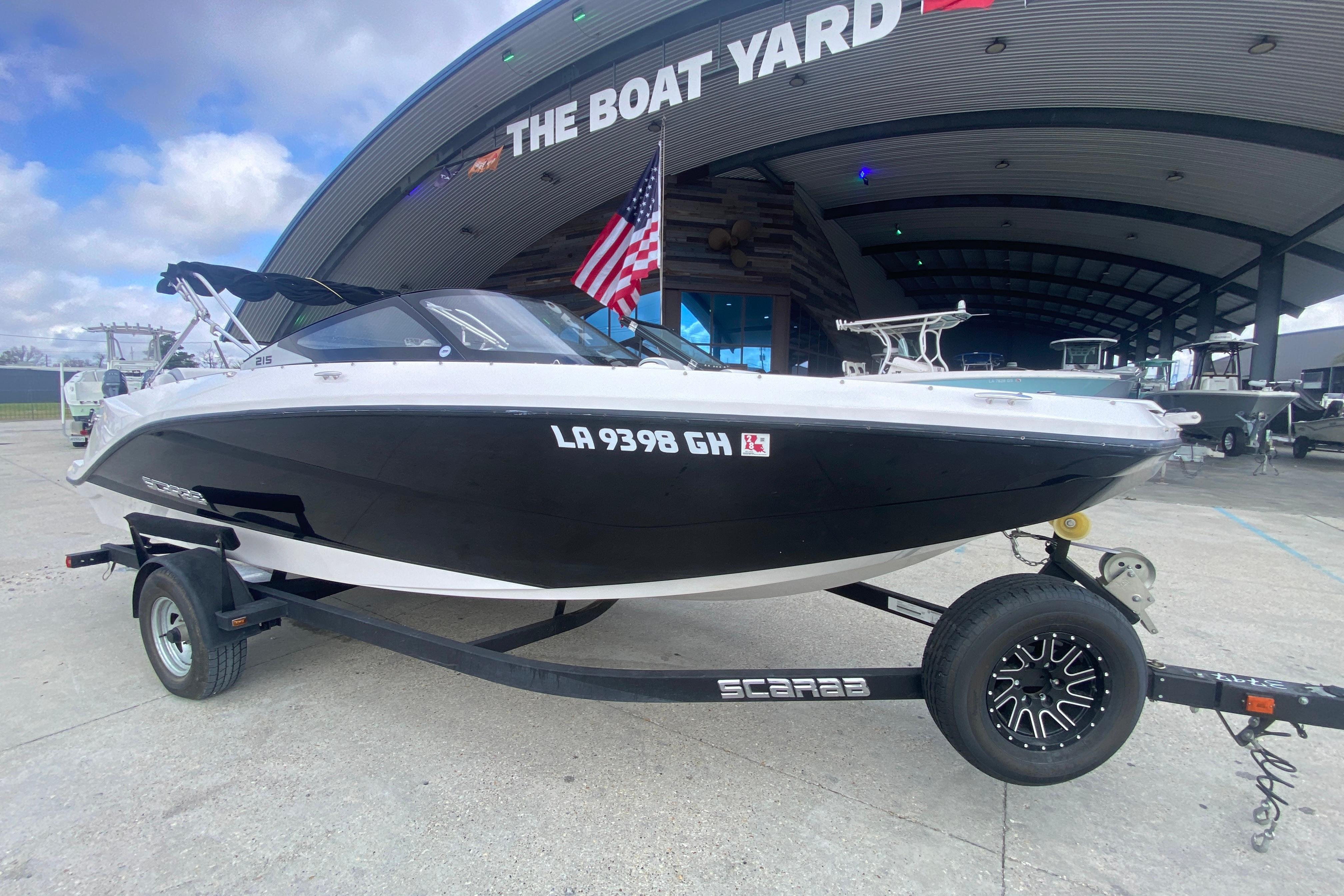 2018 Scarab 215 G boat on trailer at The Boat Yard, featuring sleek black and white design.