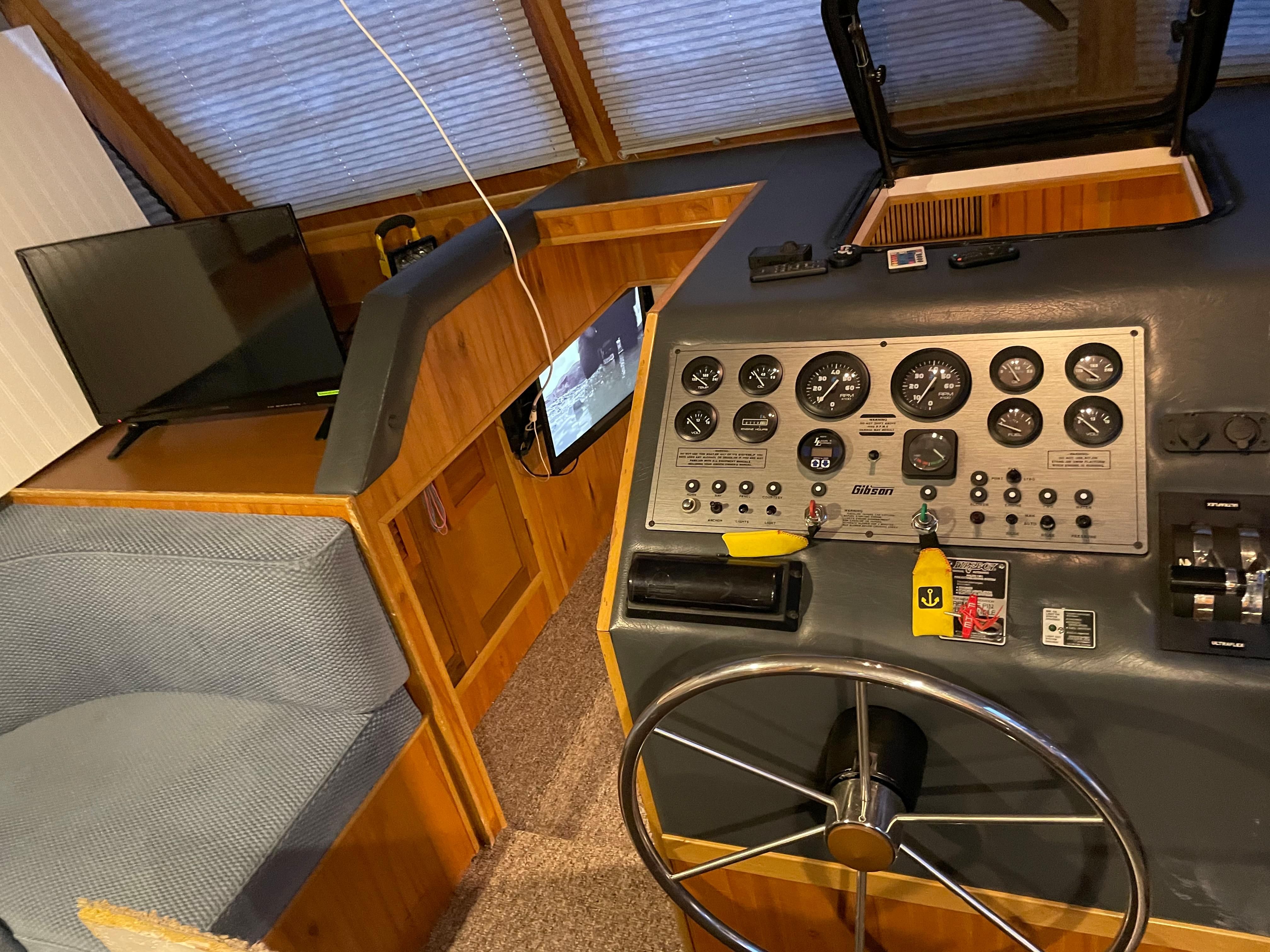 Interior view of a boat with helm, instruments, and seating area.