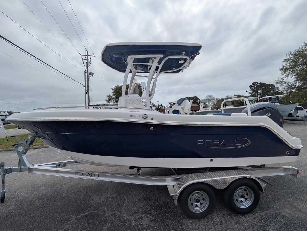 2025 Robalo R222 Explorer boat on trailer, side view, under cloudy sky.