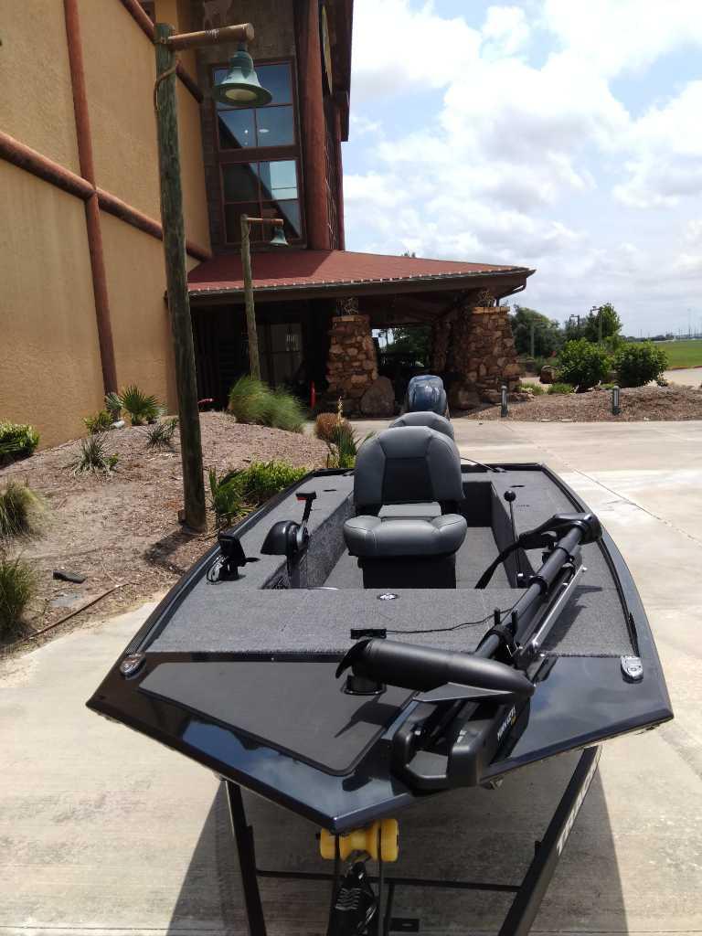 2025 Tracker Panfish 17 boat parked outside a rustic building under a cloudy sky.