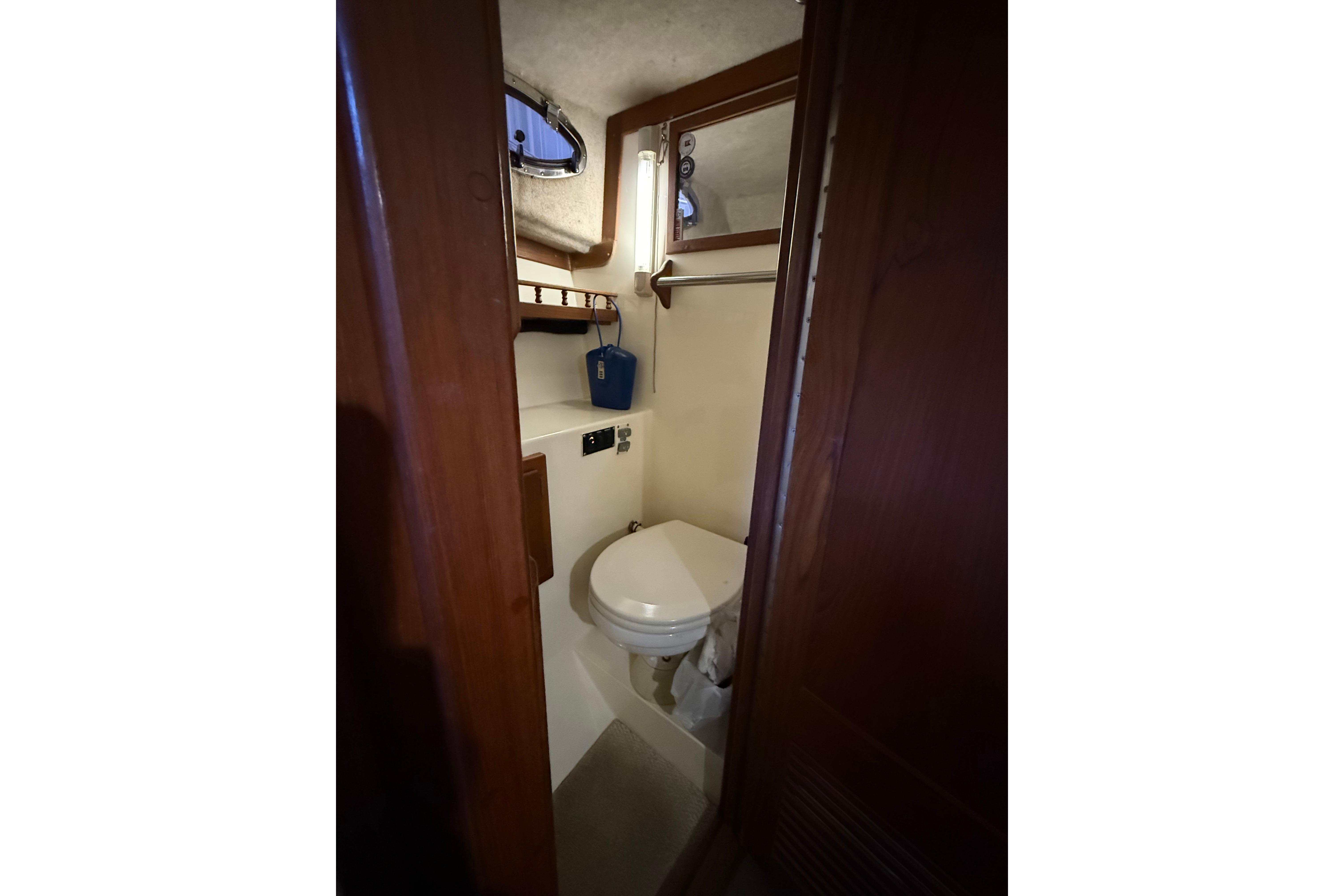 Compact bathroom inside 2002 Albemarle 265 Express Fisherman boat, featuring toilet and mirror.