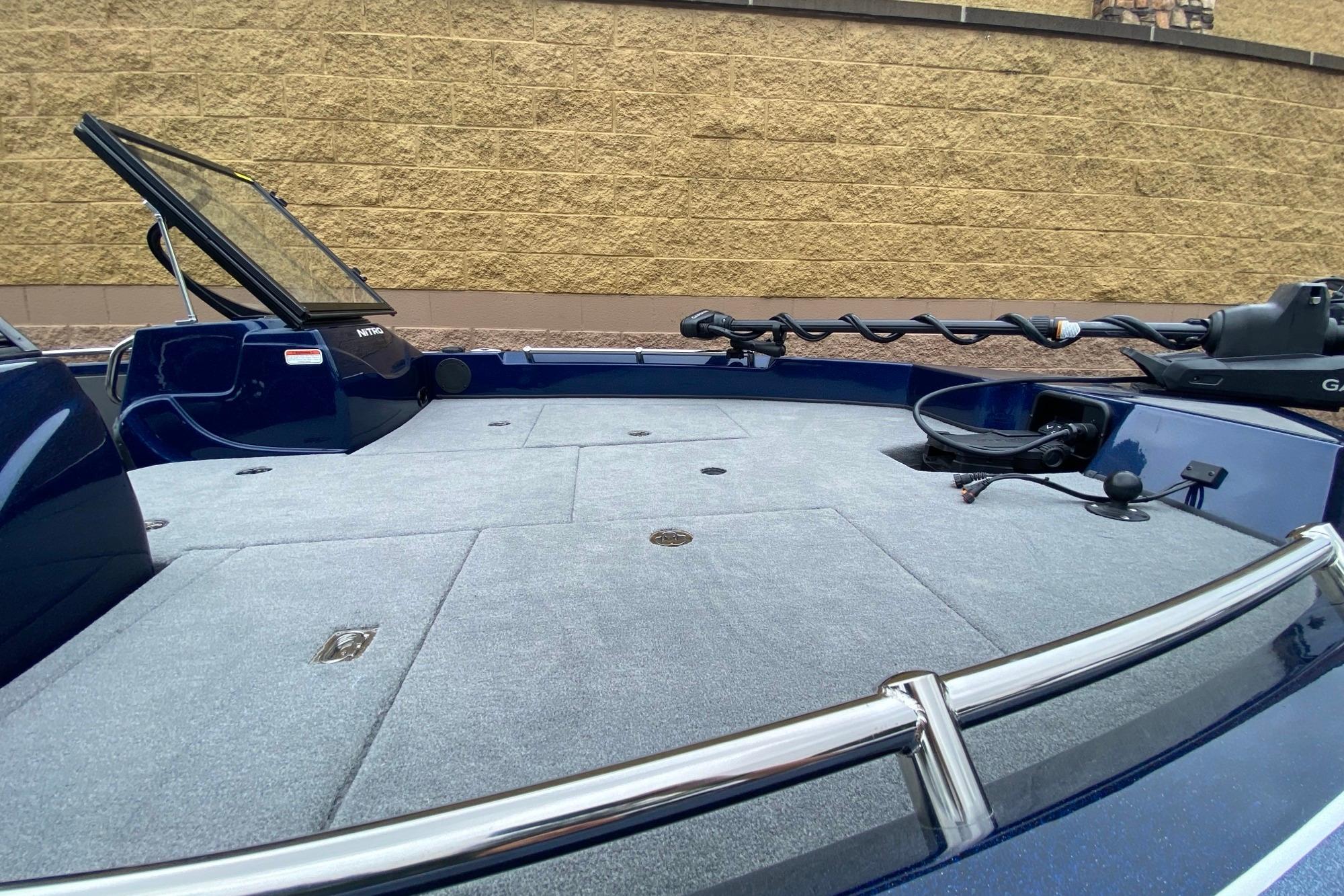2026 Nitro ZV19 Pro boat deck with trolling motor and windshield, against a brick wall backdrop.