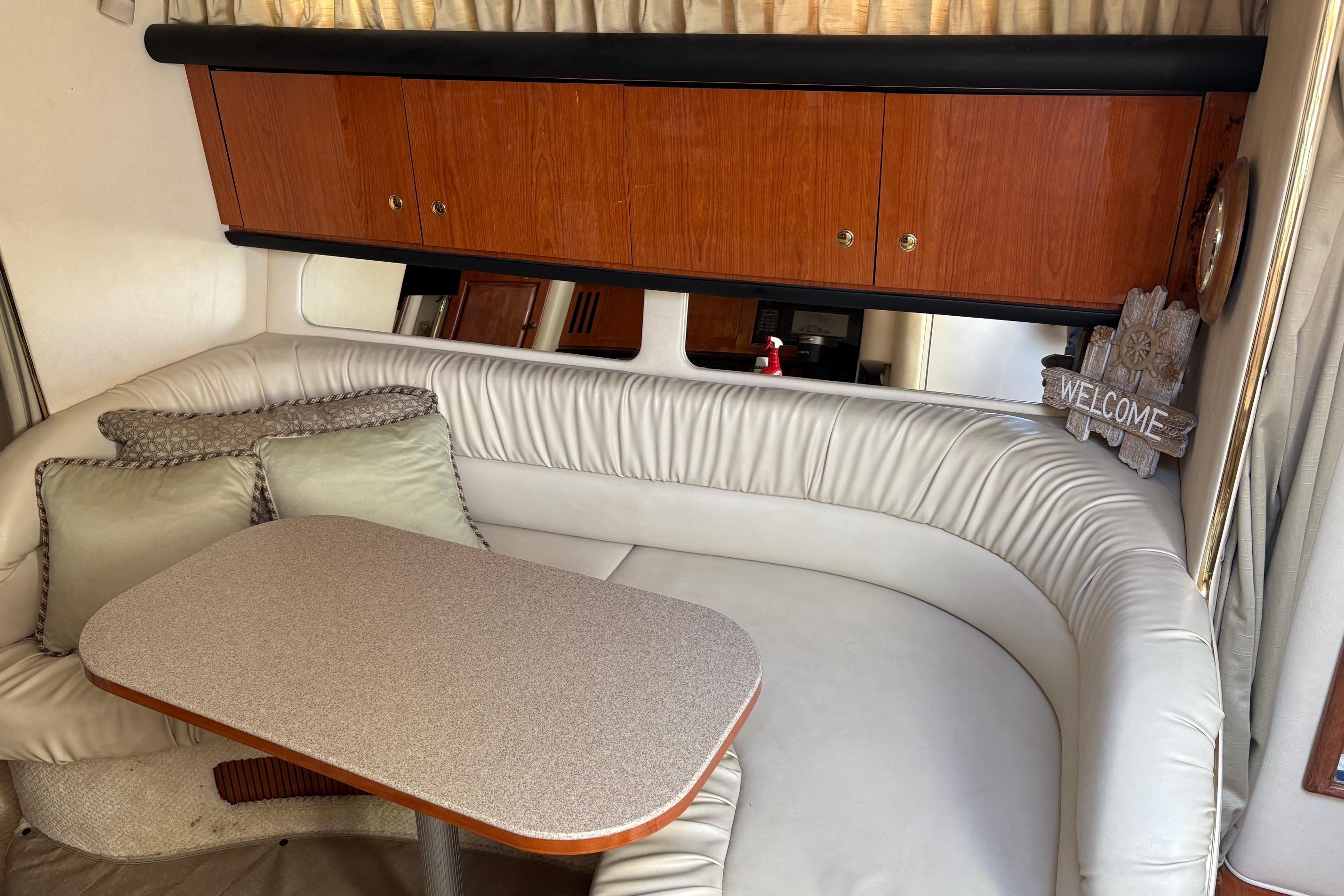 Interior of 2001 Sea Ray 340 Sundancer with cozy seating and wooden cabinets.