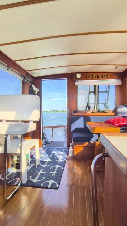 Interior of a boat with wooden flooring, white seats, and a view of the water.