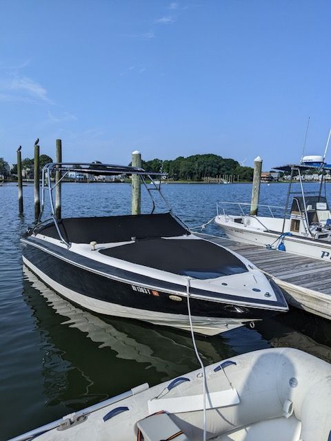 A black 2003 Cobalt 240 boat is docked in calm waters.