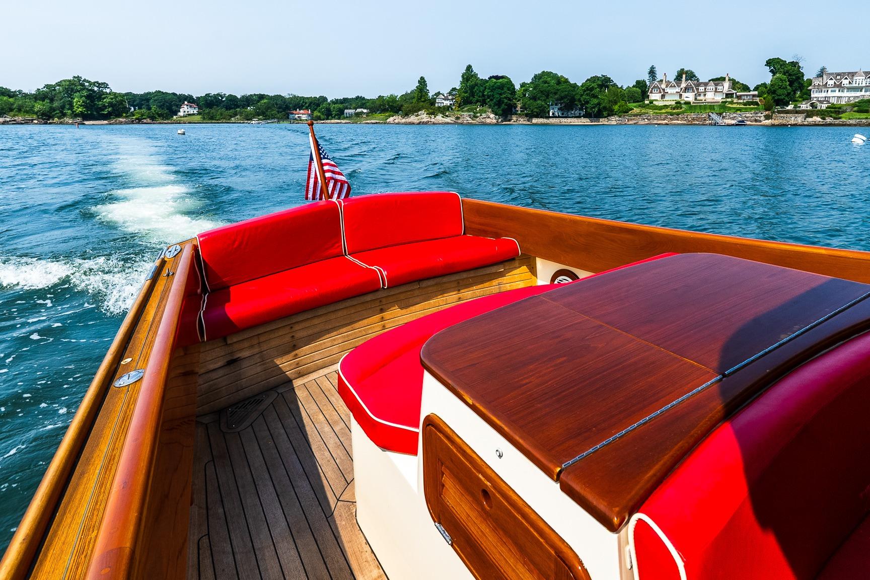 2005 Hinckley Talaria 29R boat with red seating, cruising on a scenic lake.