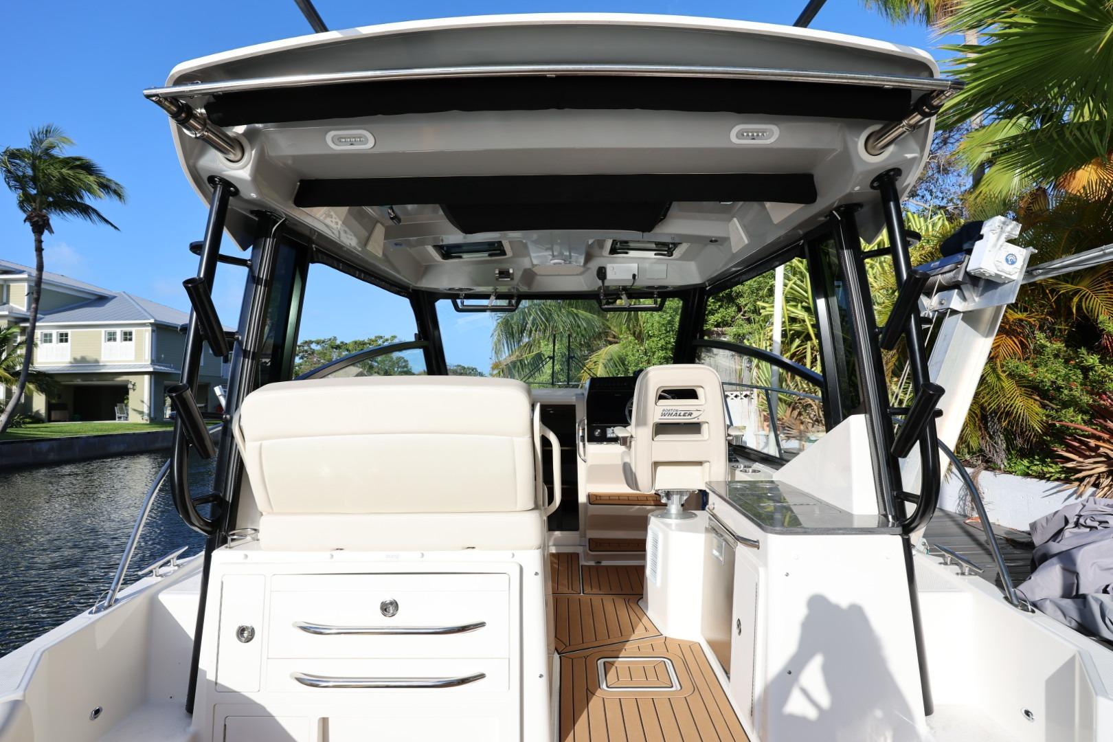 2025 Boston Whaler 325 Conquest boat interior with seating and helm, docked by a canal.