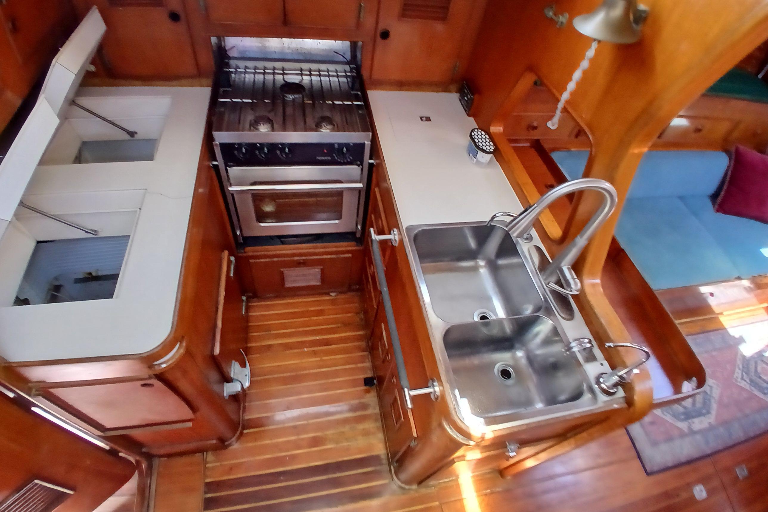 1981 SKYE 51 yacht kitchen with dual sinks, stove, and wooden cabinetry.