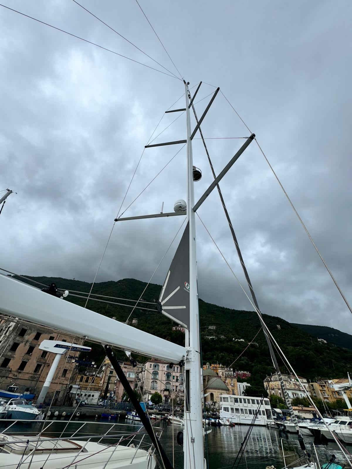 2023 Jeanneau 65 sailboat mast against cloudy sky in marina setting.