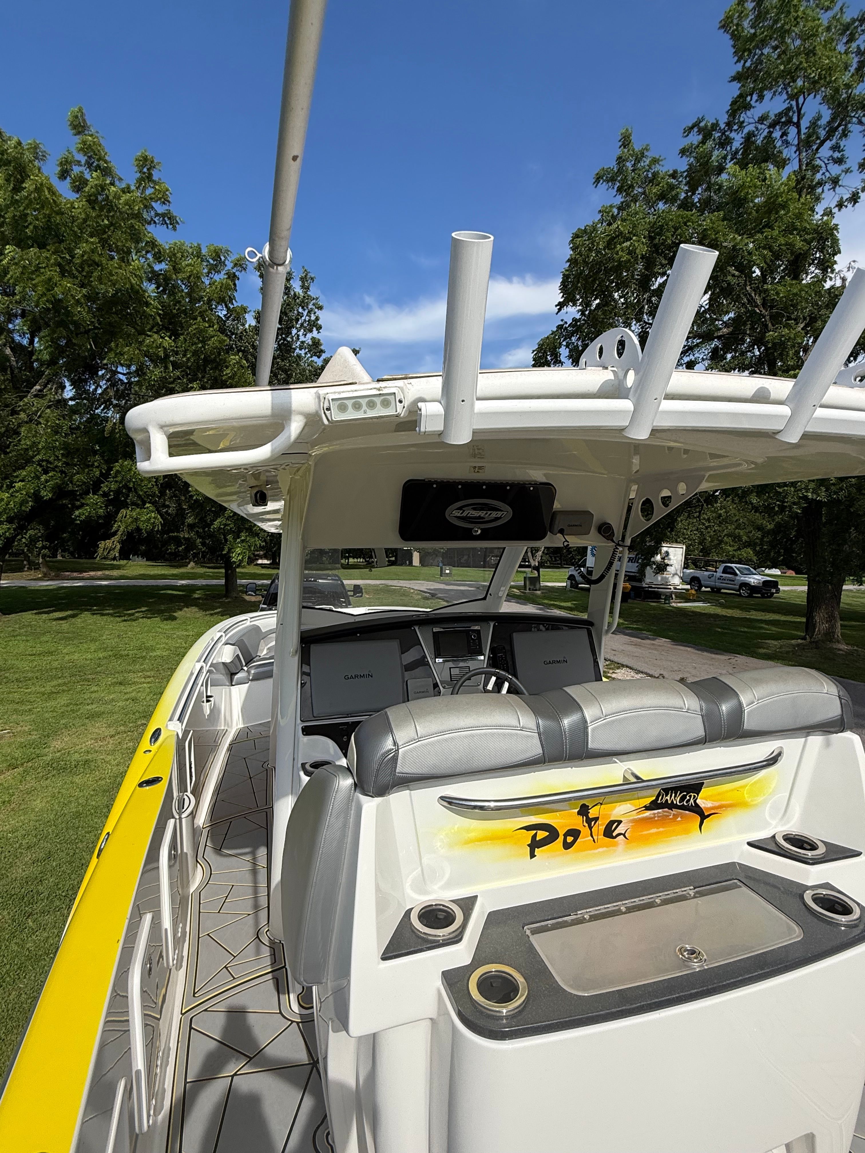 A 2014 Sunsation 34 CCX boat with gray seats and yellow accents, parked on grass.