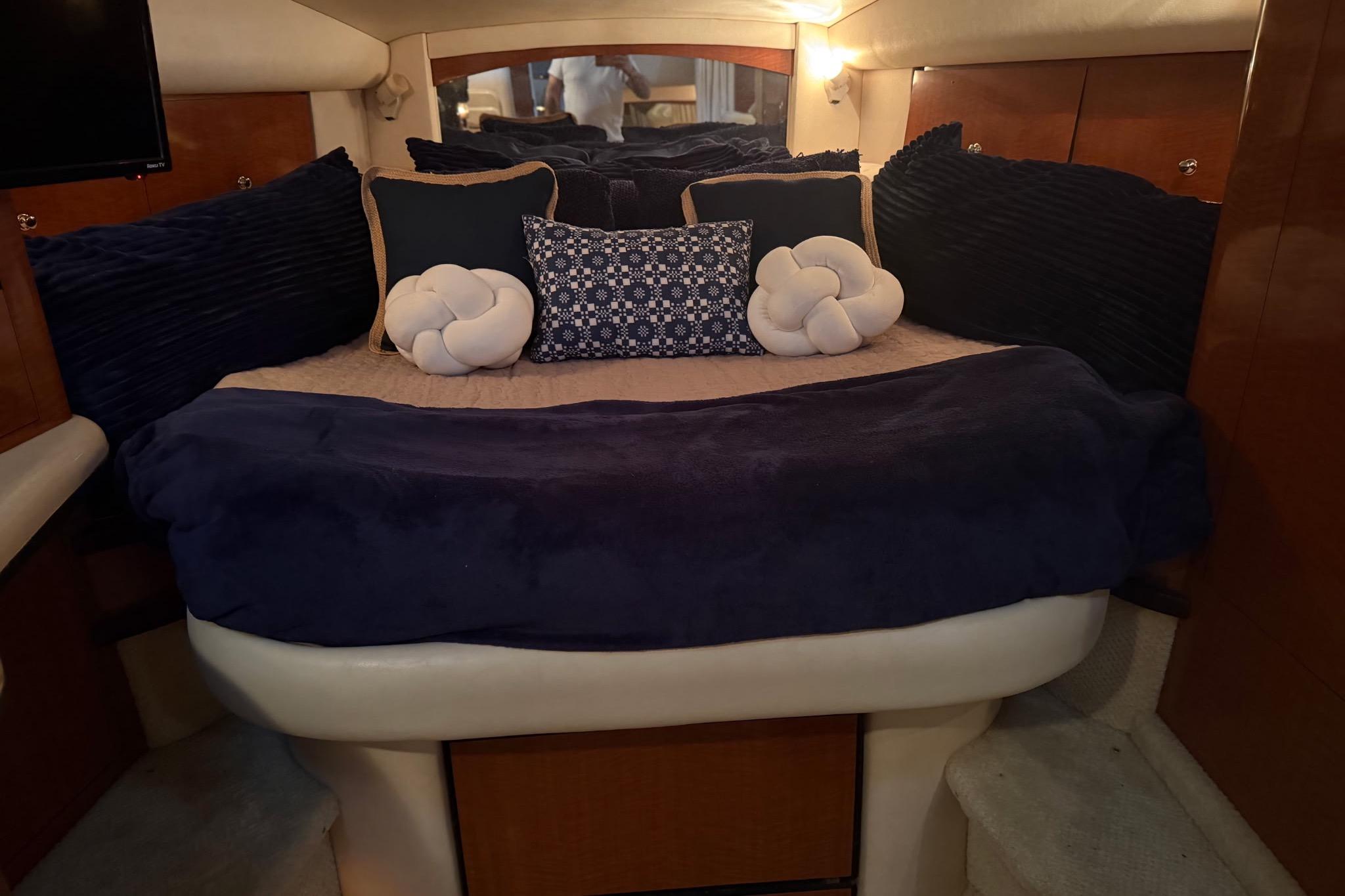 Luxurious cabin interior of 2002 Sea Ray Sundancer 320 with plush bedding and cushions.